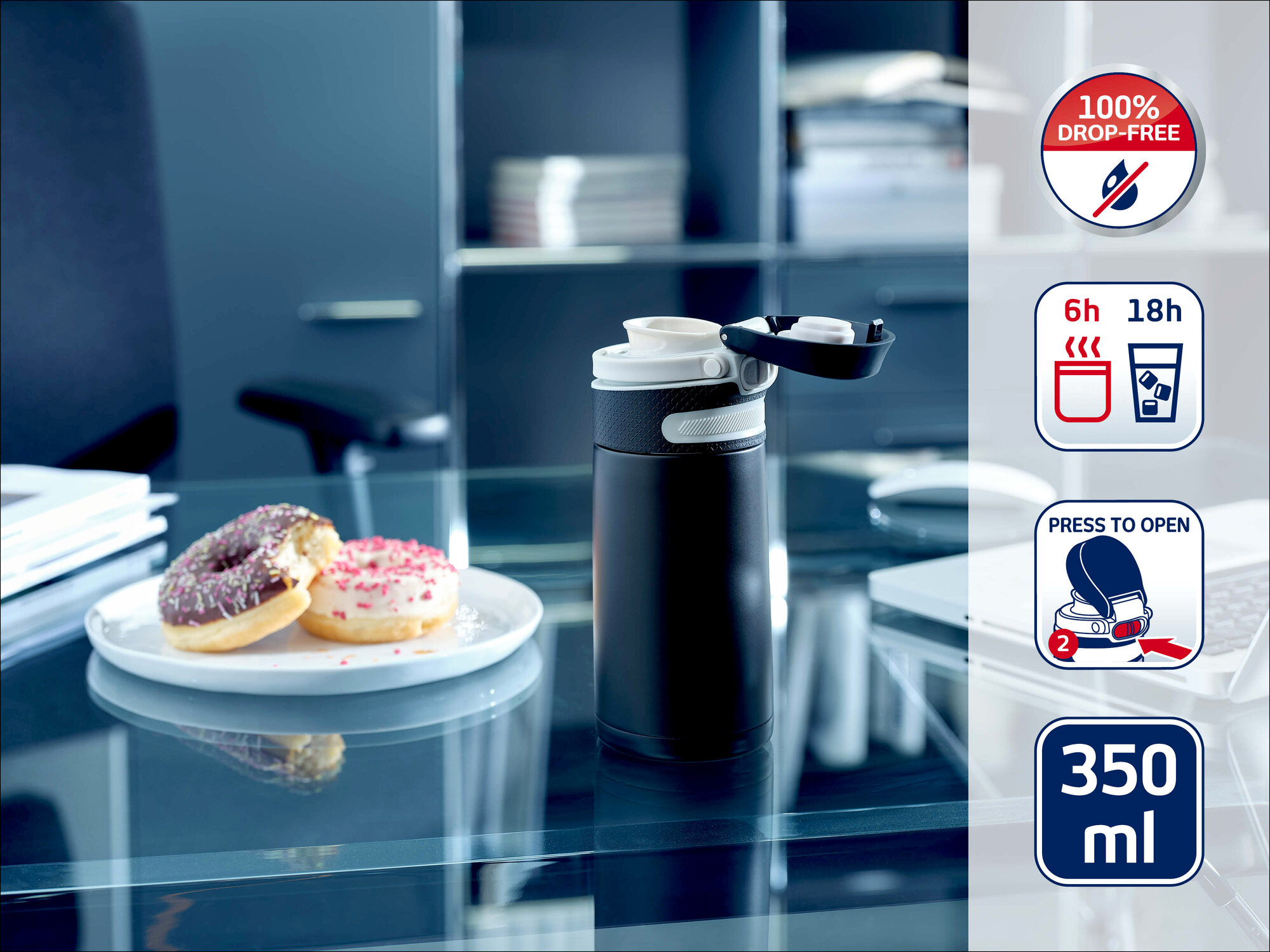 Ein schwarzer Isoliarbecher steht auf einem Glastisch neben einem Teller mit zwei Donuts im Büro.