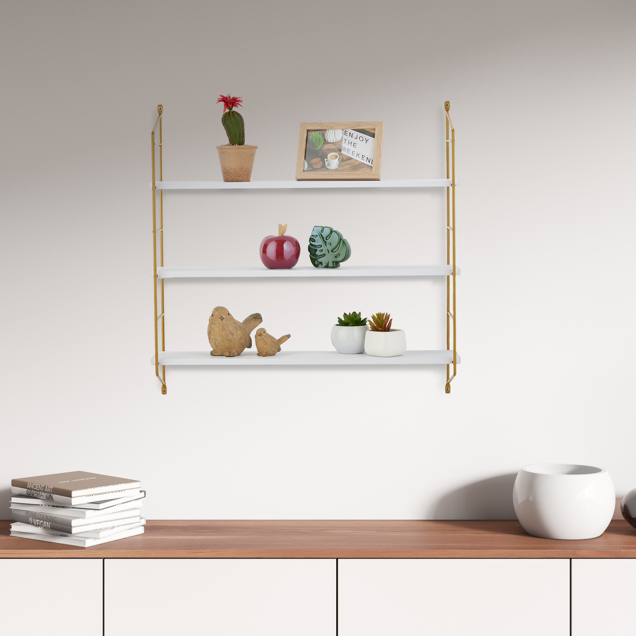 Wandregal mit Dekoration über einer Holzkommode mit Büchern.