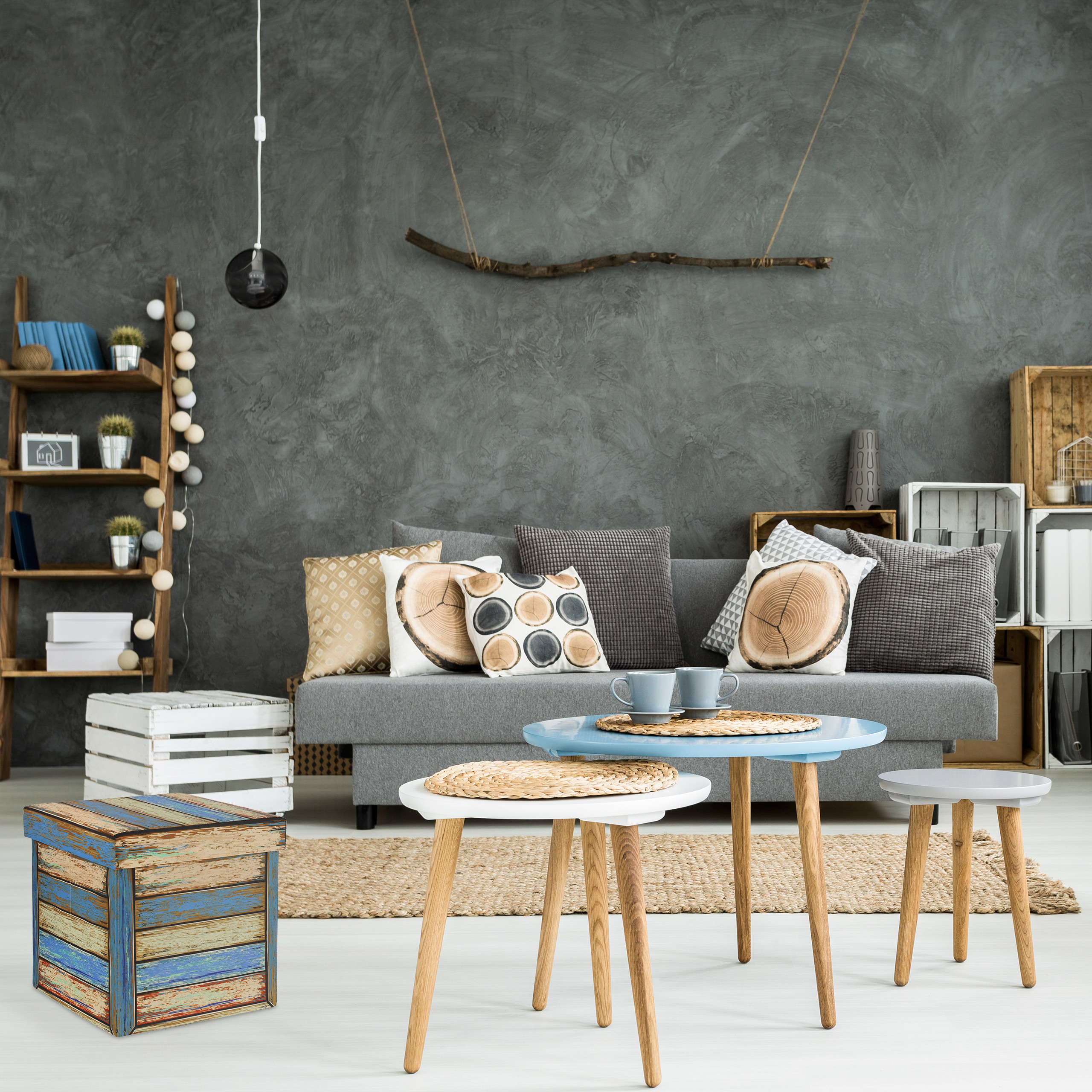 Gemütliches Wohnzimmer mit grauem Sofa, Holztischchen, Regal und grauer Wand mit Ast.
