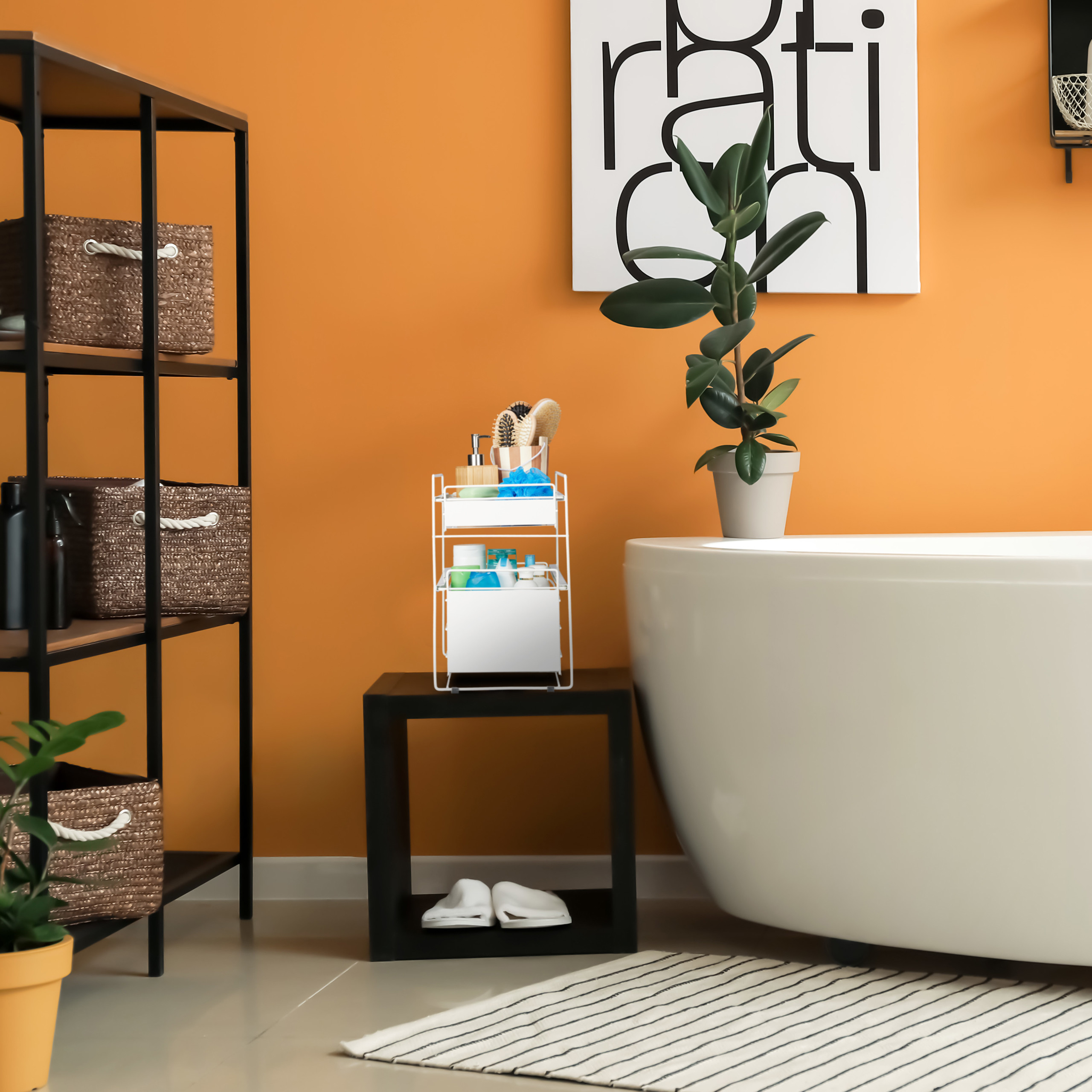 Badezimmer mit weißer Wanne, orangen Wänden, schwarzem Regal mit Körben und einer kleinen Pflanze.