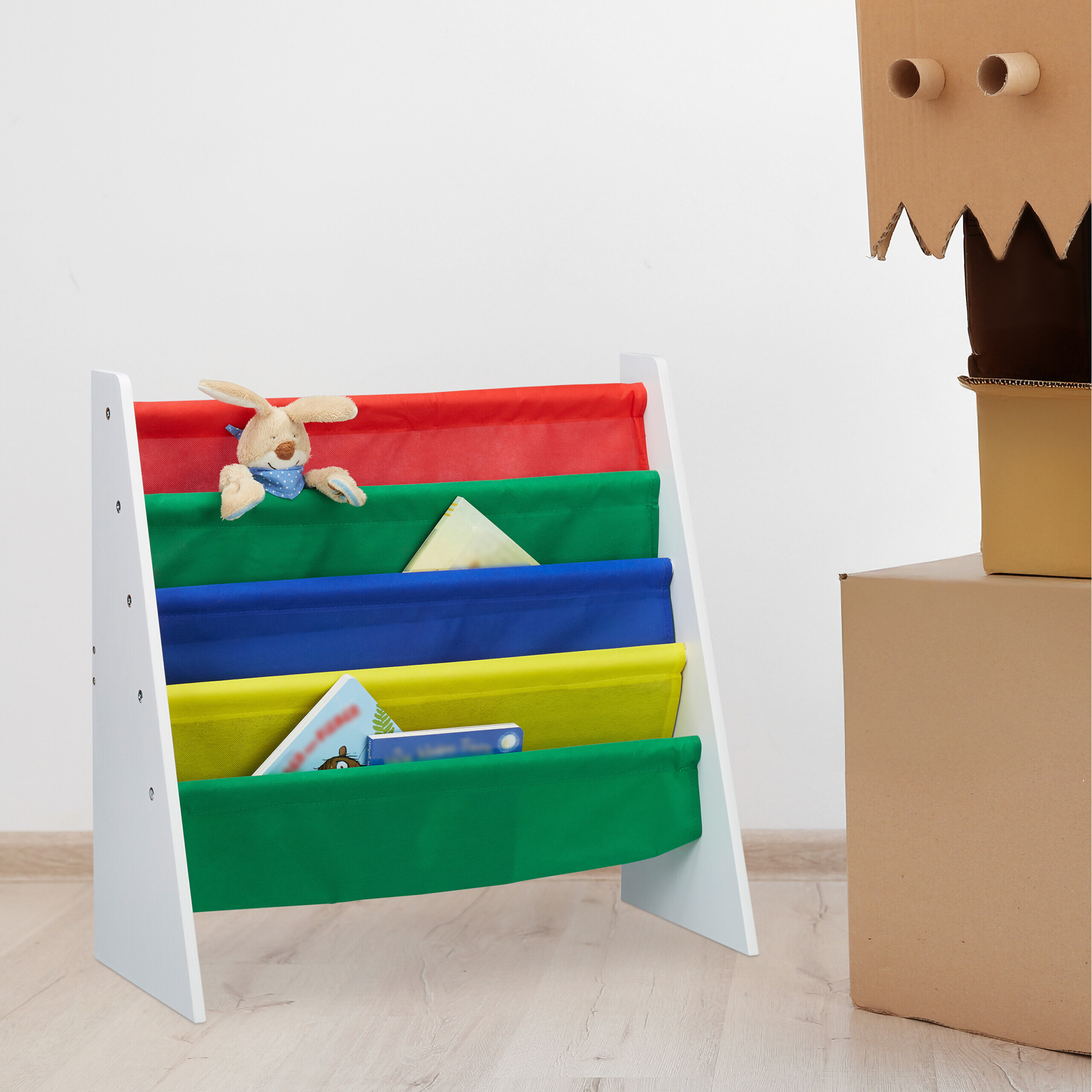 Bunte Kinderbuchregal mit Plüschhase und Kinderbüchern, daneben ein Kartonroboter.