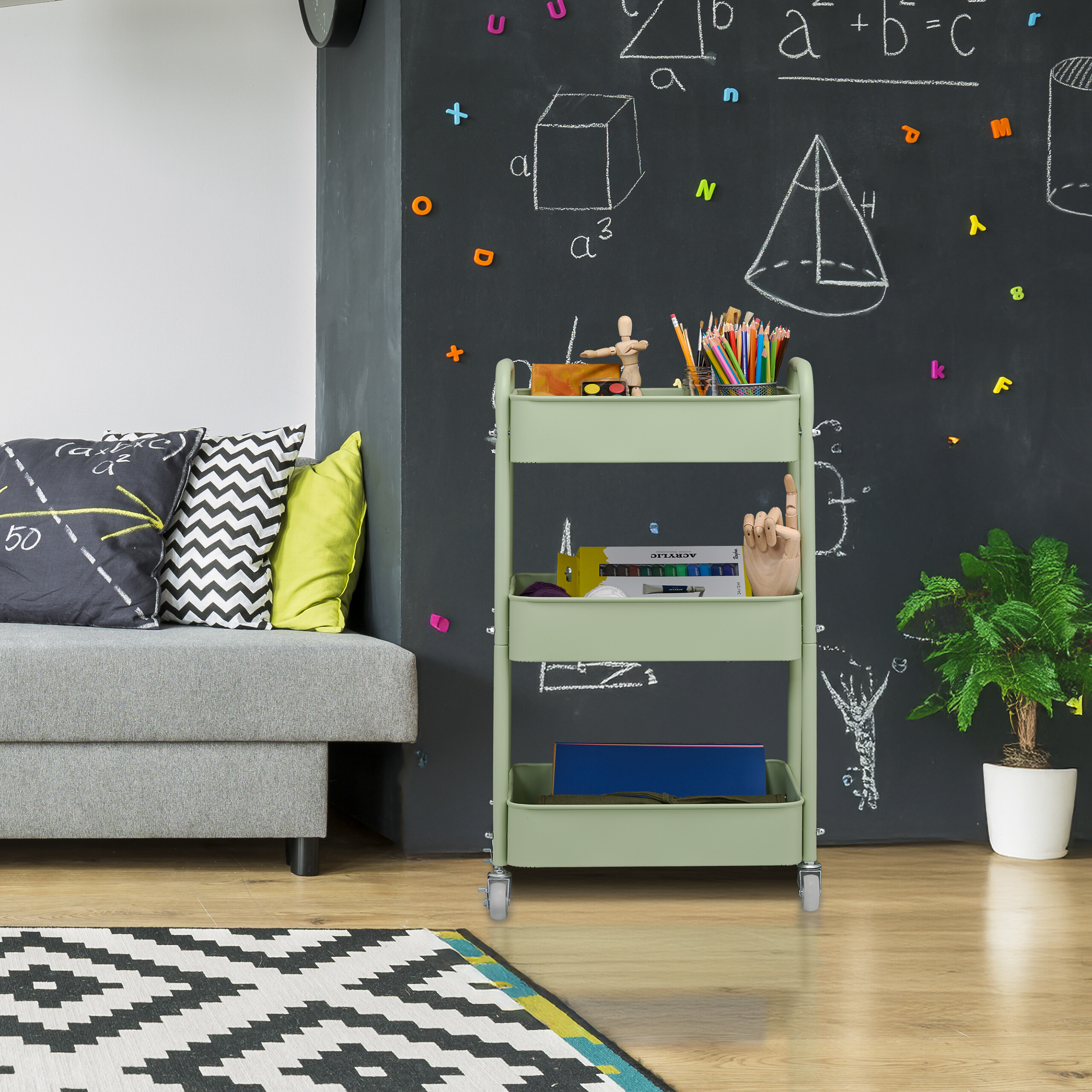 Grüner Rollwagen vor Tafel mit geometrischen Zeichnungen, neben grauem Sofa und Topfpflanze.