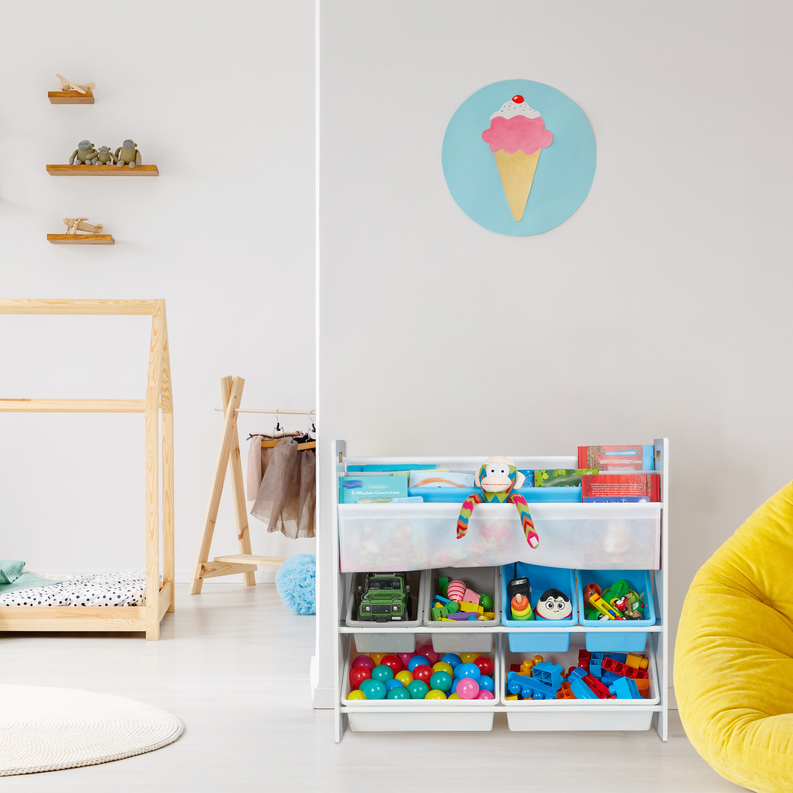 Buntes Kinderzimmer mit Spielzeugregal, Holzbett und Eistüten-Wandbild auf weißer Wand.