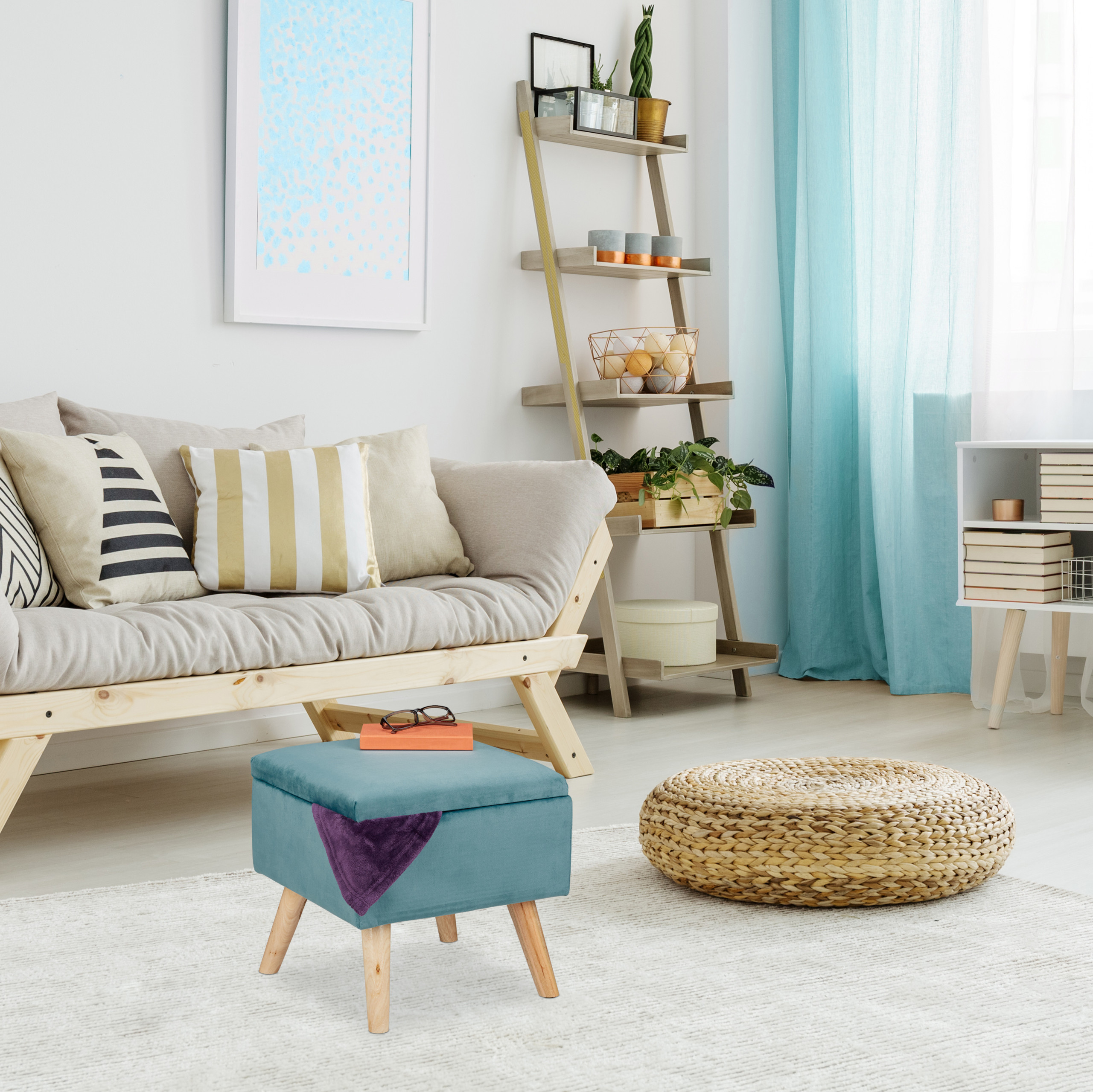 Gemütliches Wohnzimmer mit beigem Sofa, blauem Hocker, hölzernem Regal und Vorhängen in Blau.