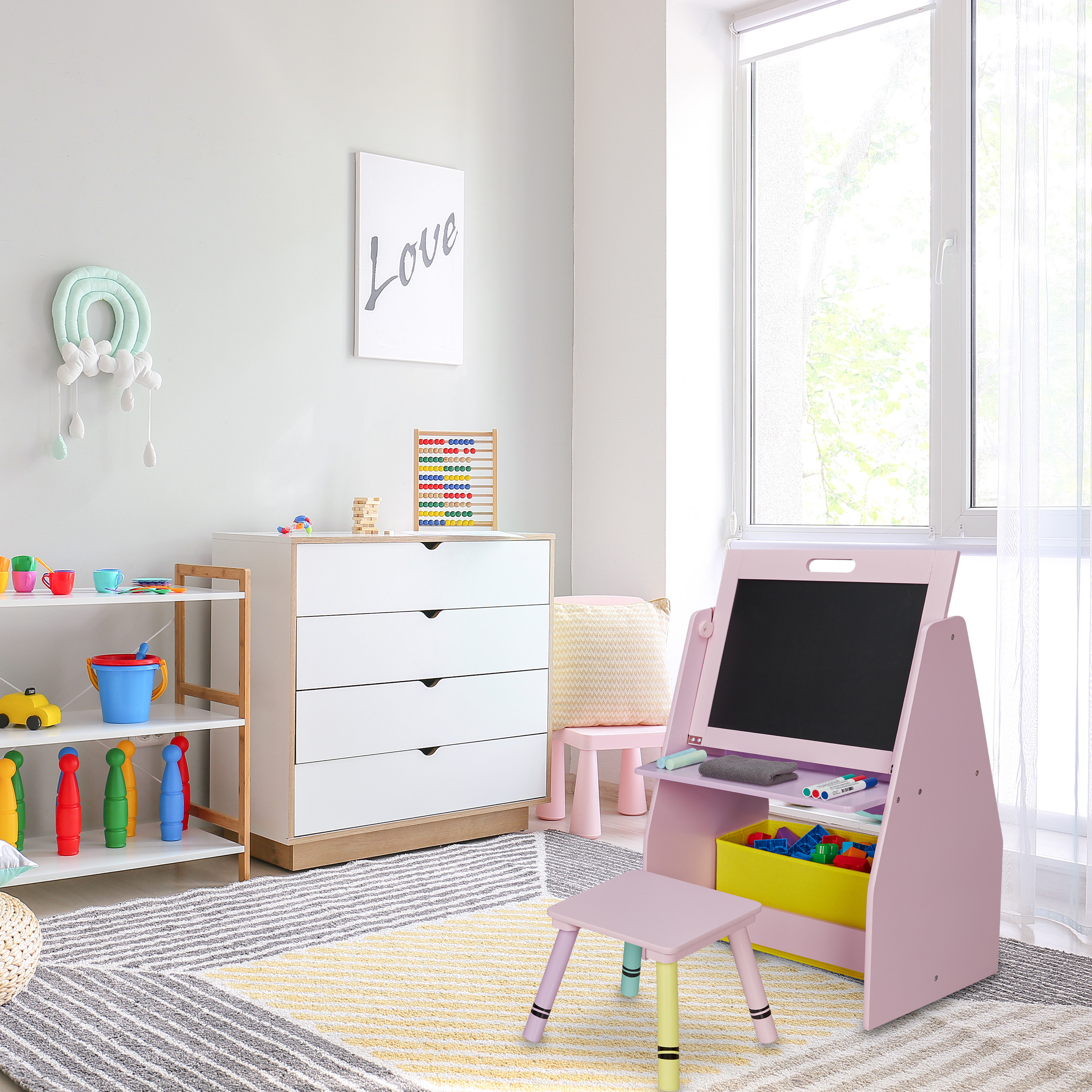 Ein helles Kinderzimmer mit einer Maltafel, einer weißen Kommode, Spielzeugregalen und einem gemusterten Teppich.