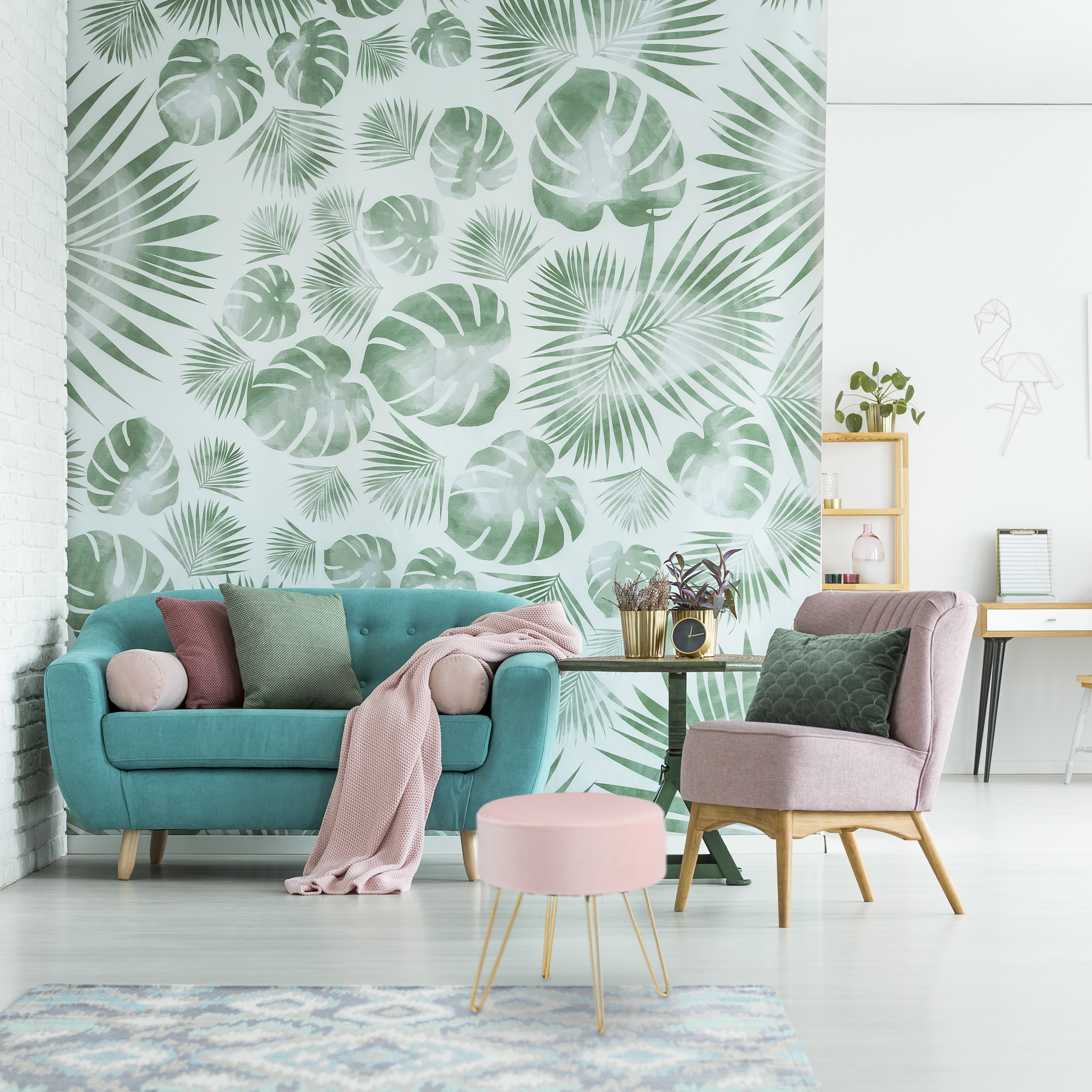 Helles Wohnzimmer mit tropischer Blatttapete, türkisem Sofa, rosa Sessel und kleinem Hocker.