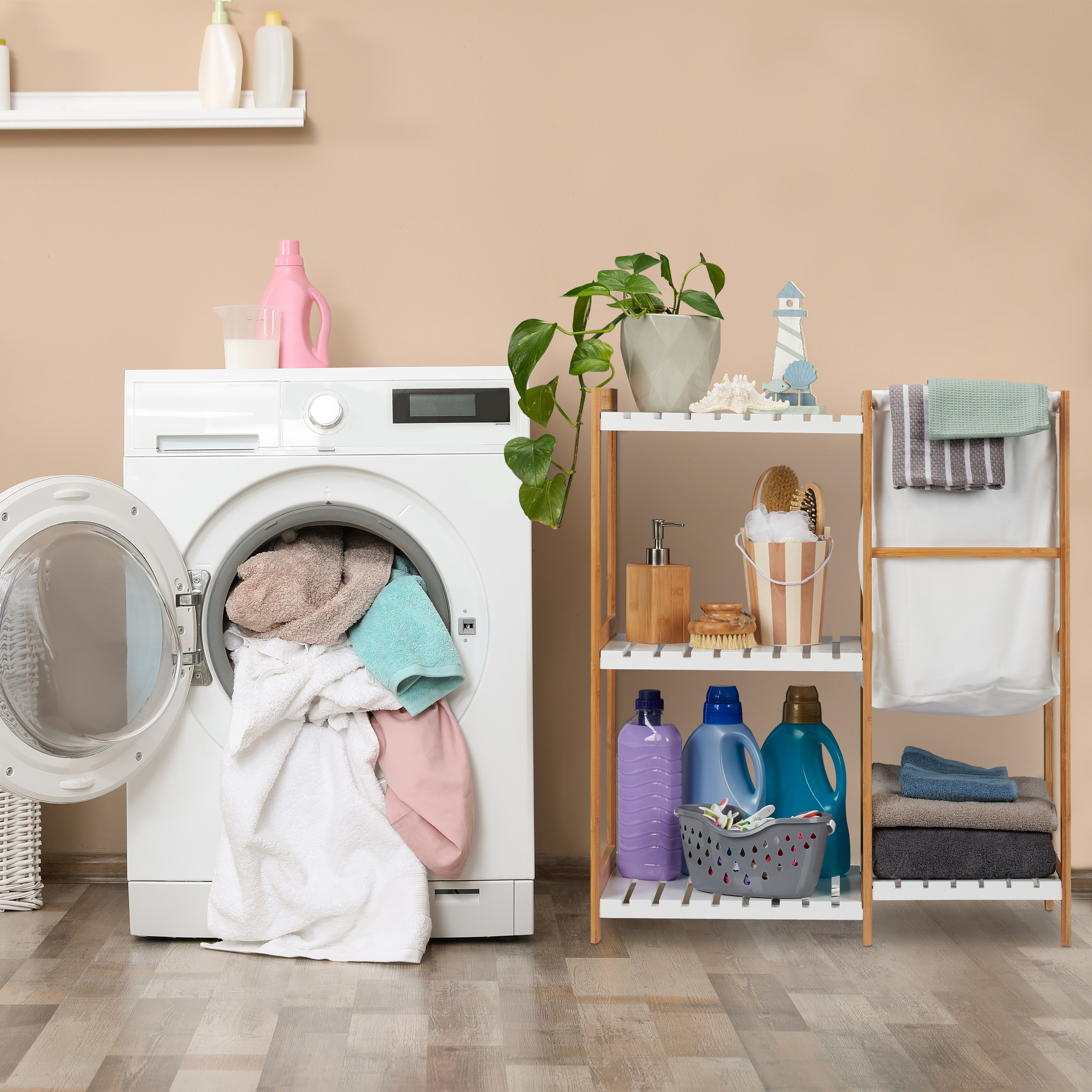 Eine weiße Waschmaschine mit offener Tür und Wäsche. Neben ihr steht ein Holzregal mit Waschmitteln und Handtüchern.