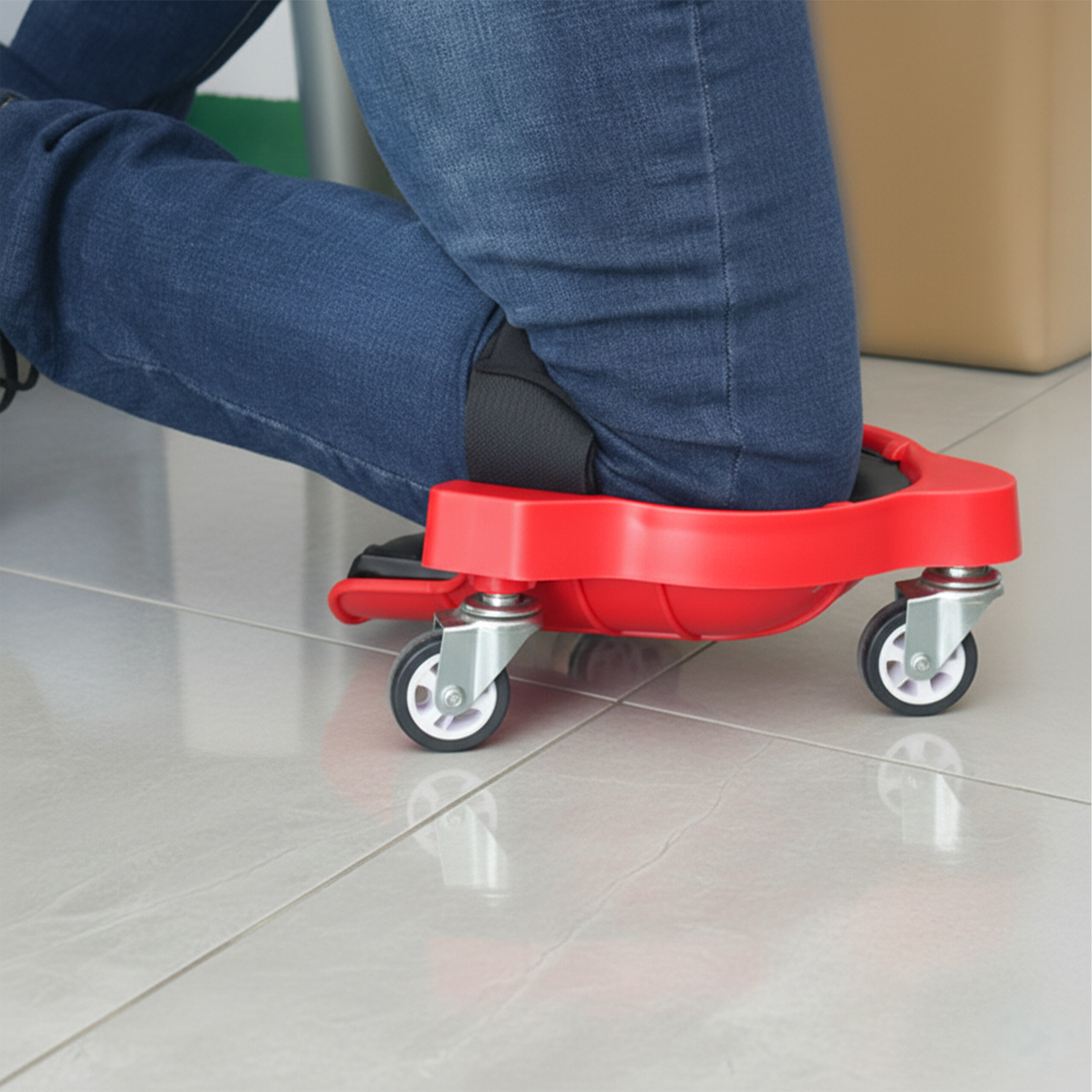 Eine Person kniet auf einer roten Rollkniestütze mit schwarzen Gurten auf Fliesen.