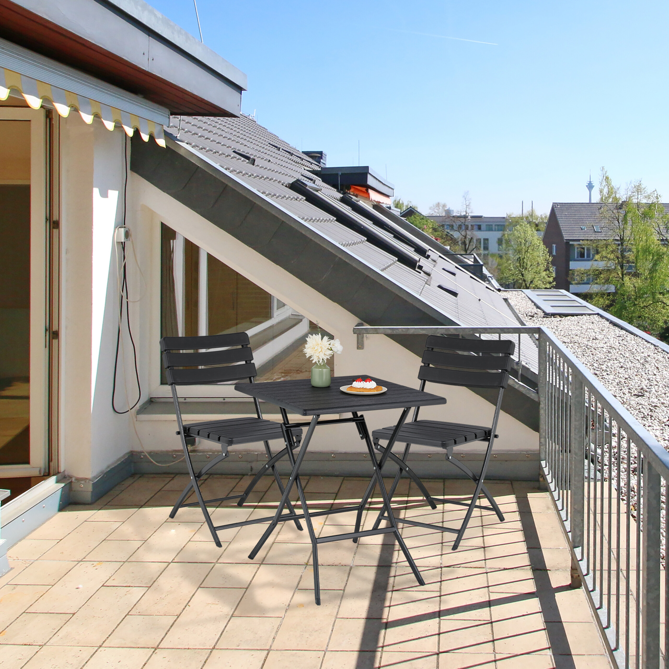Ein kleiner Tisch mit zwei Stühlen auf einer sonnigen Dachterrasse mit Blick auf Gebäude.