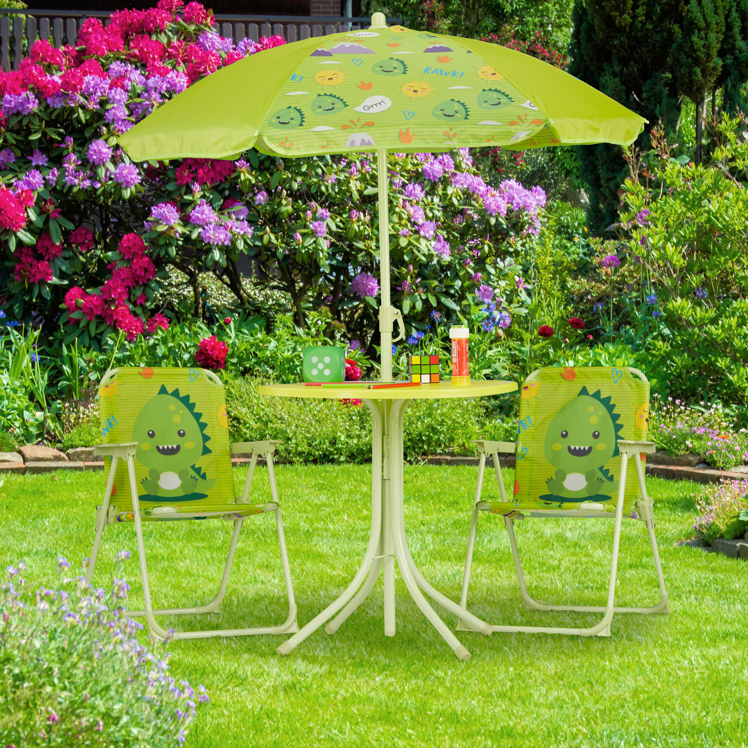 Grüner Kindertisch mit Regenschirm und zwei Stühlen mit Dinosaurier-Motiv auf einem Gartenrasen.