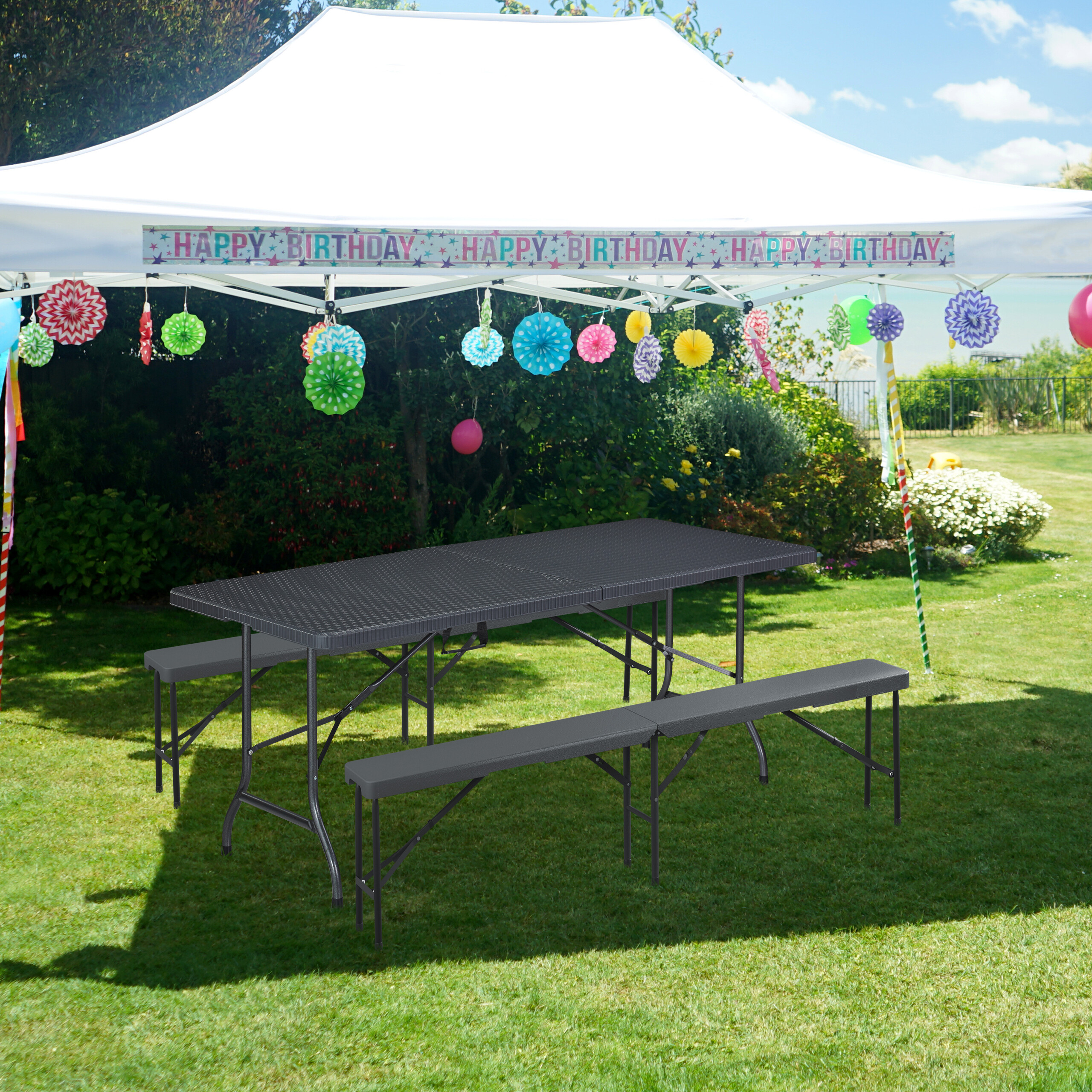 Ein schwarzer Klapptisch und Bänke unter einem weißen Partyzelt auf grünem Gras.