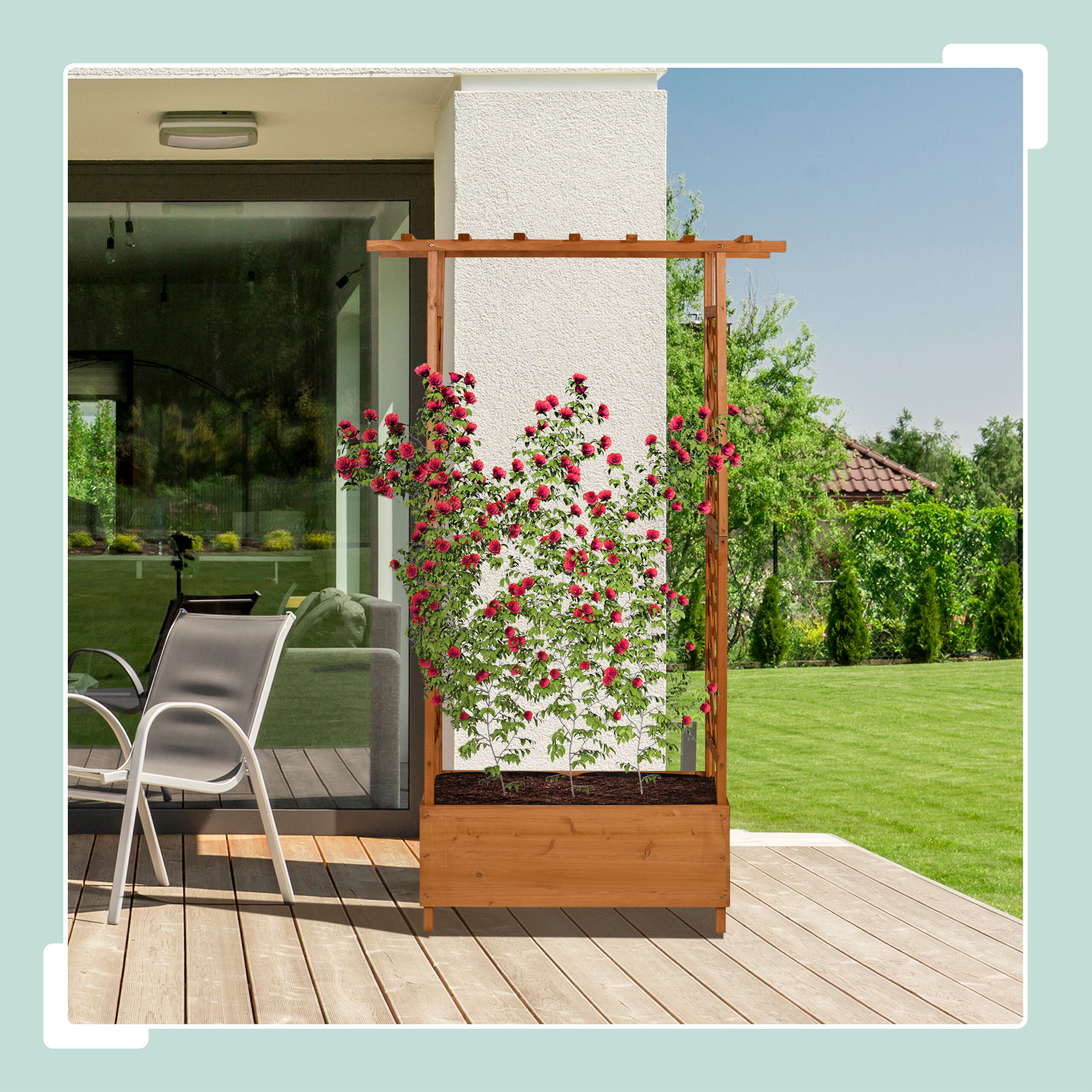 Ein hölzernes Pflanzgefäß mit Spalier und roten Rosen steht auf einer Holzterrasse vor einem Haus.