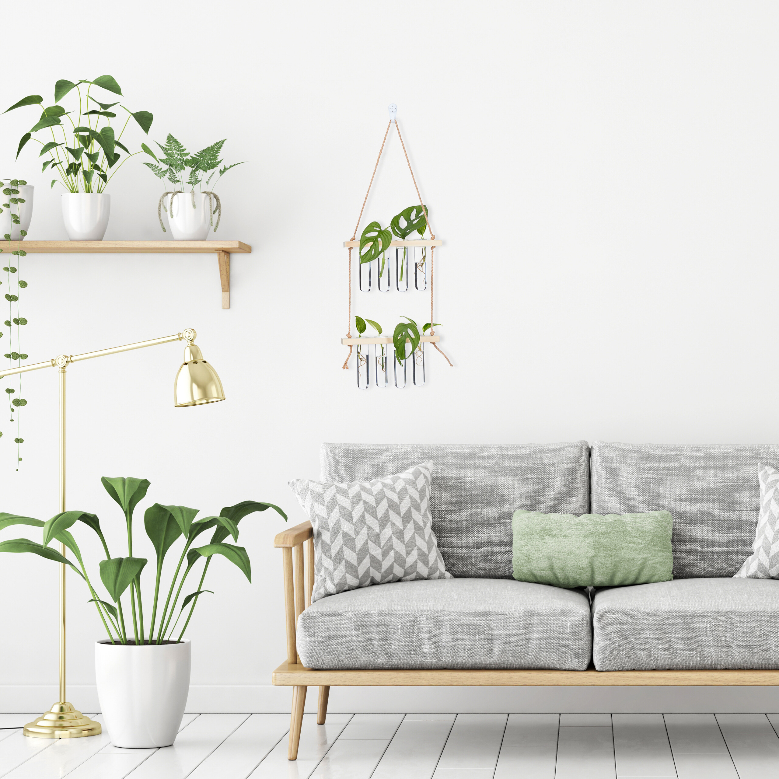 Ein graues Sofa mit Kissen steht vor einer weißen Wand neben Zimmerpflanzen, einer Lampe und einem Wandregal.