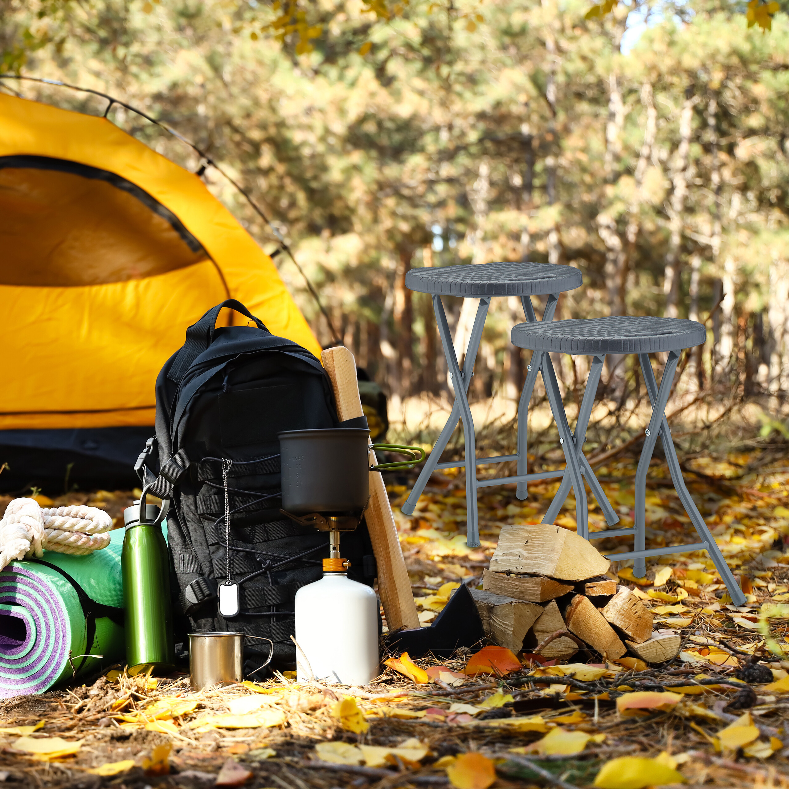 Campingausrüstung vor gelbem Zelt im Wald mit zwei grauen Hockern.