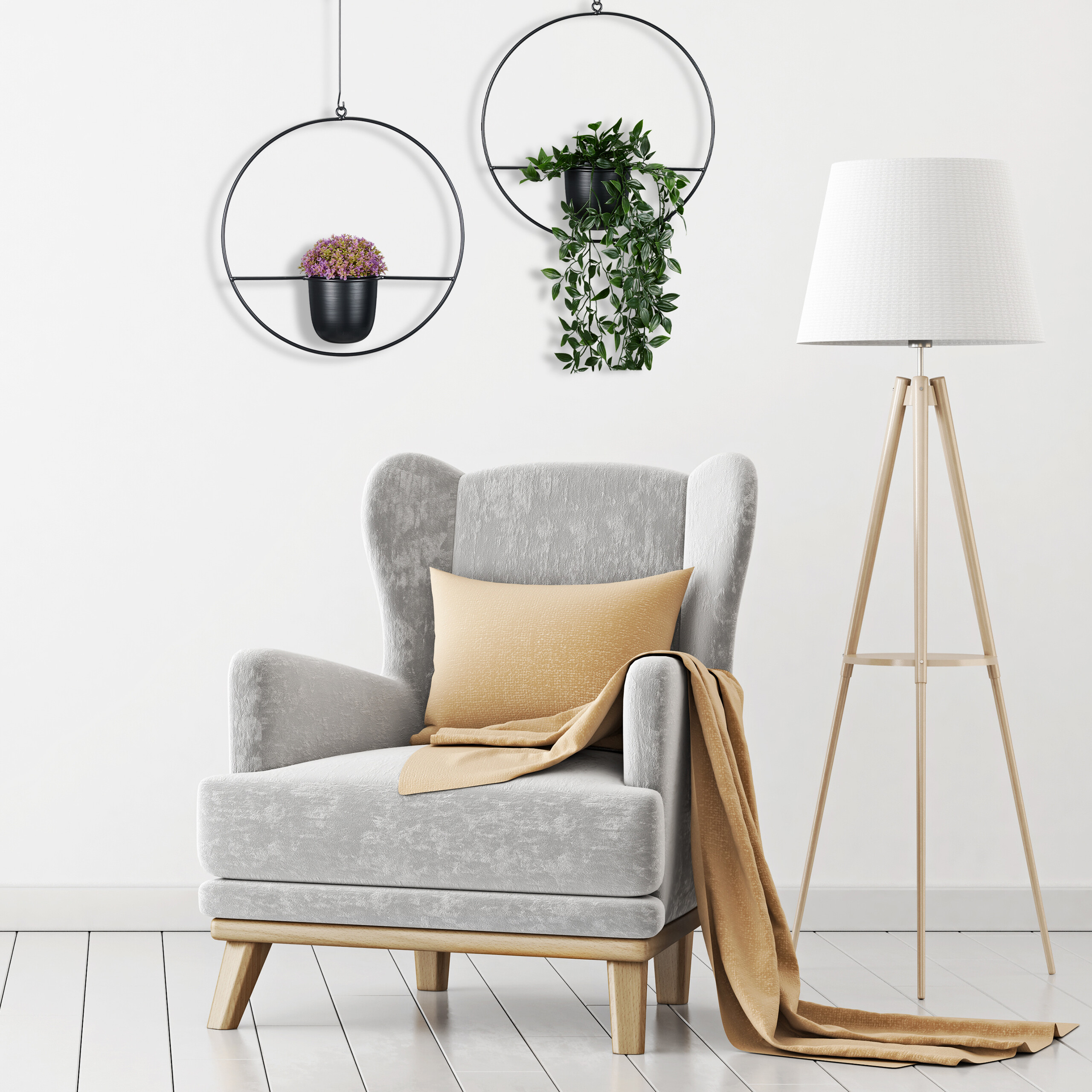 Ein grauer Sessel mit gelbem Kissen und Decke, neben Stehlampe und Hängepflanzen an weißer Wand.