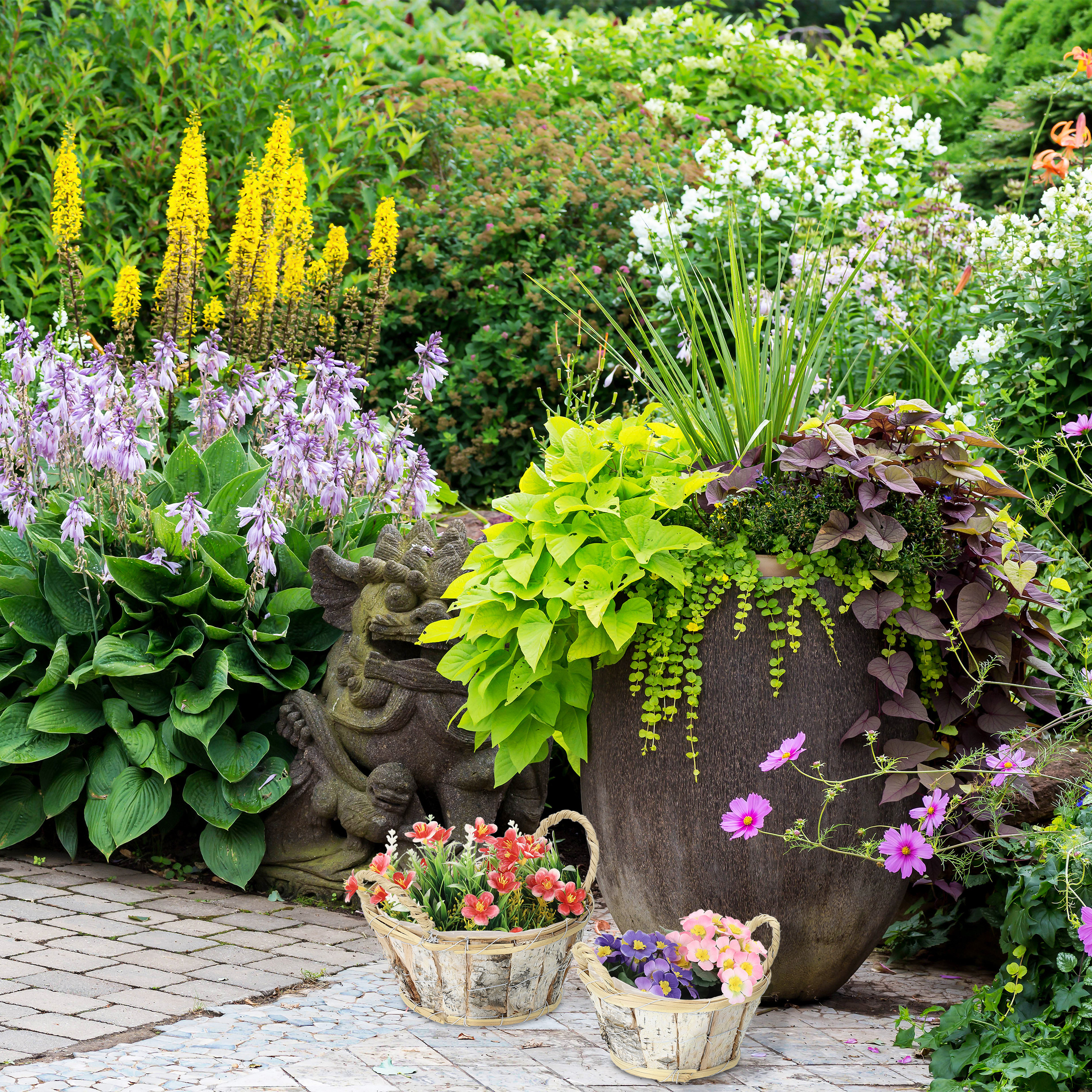 Lush garden with a large pot, flowers, and a stone gargoyle statue.