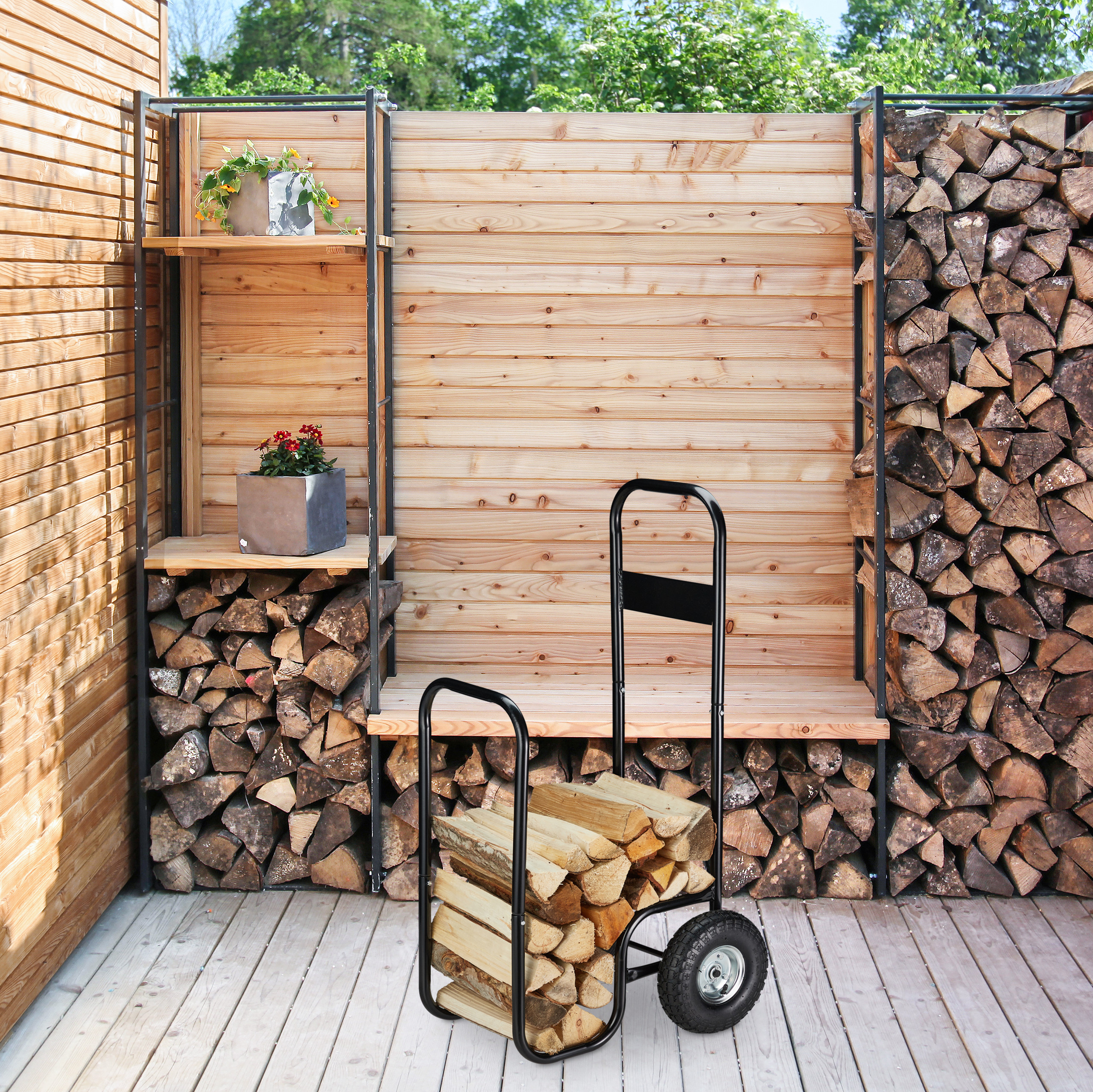 Ein schwarzer Kaminholzkarren mit Holzscheiten steht auf einer Holzterrasse vor einer Holzwand.