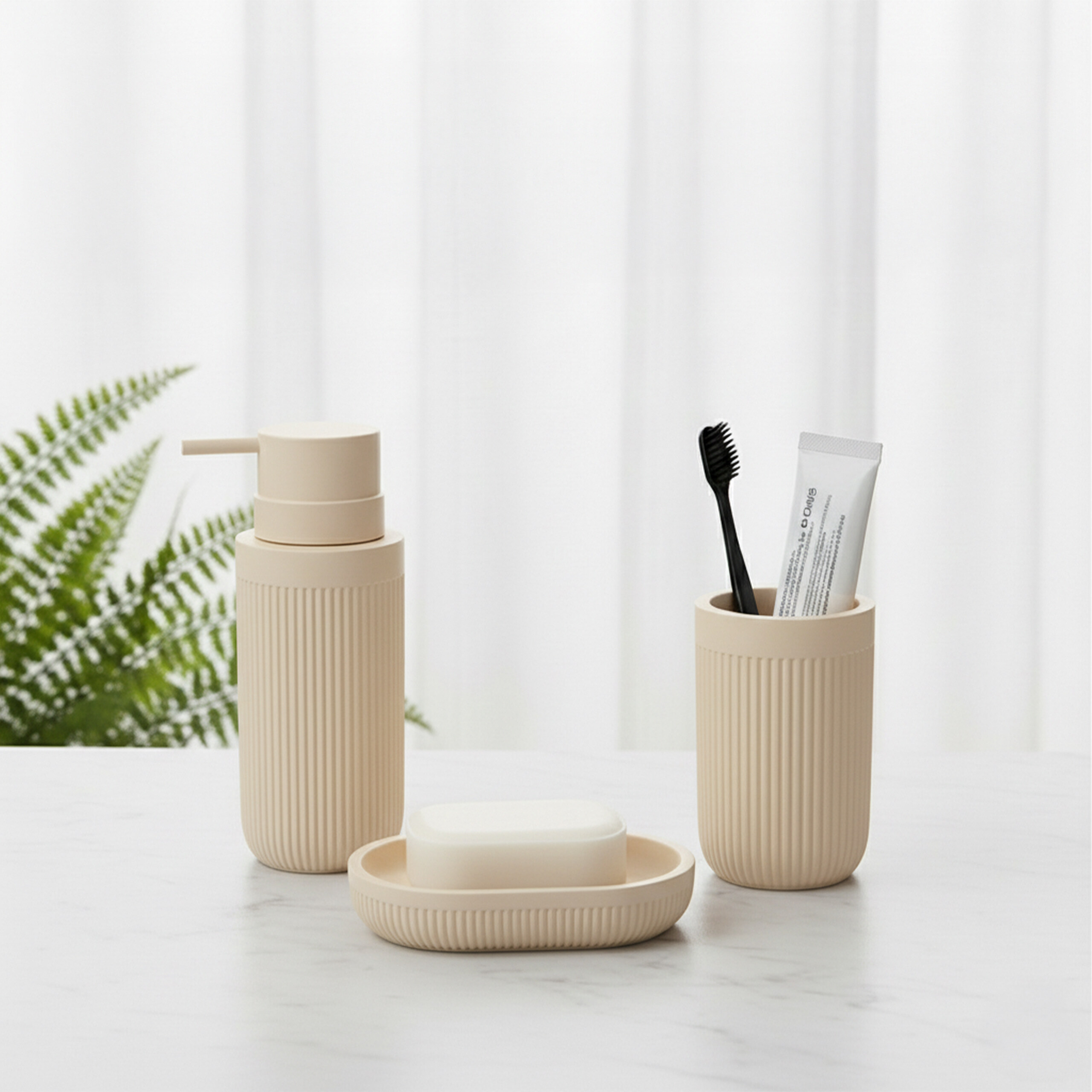 Beige Badezimmer-Accessoires wie Seifenspender, Seifenschale mit Seife und Becher mit Zahnbürste auf weißem Tisch.
