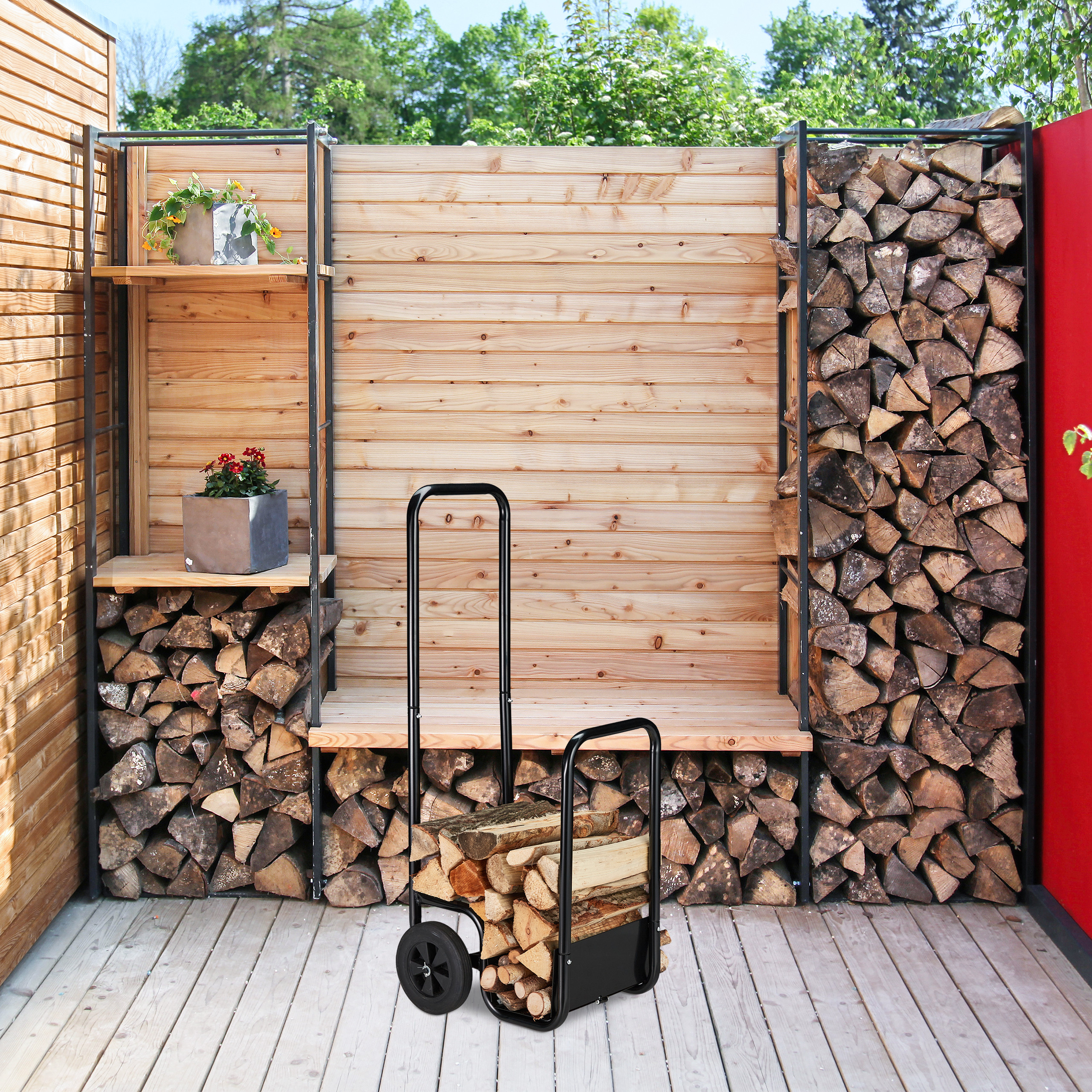 Ein Holzwagen mit Scheite steht vor einer Holzwand mit gestapeltem Kaminholz und zwei Regalen.