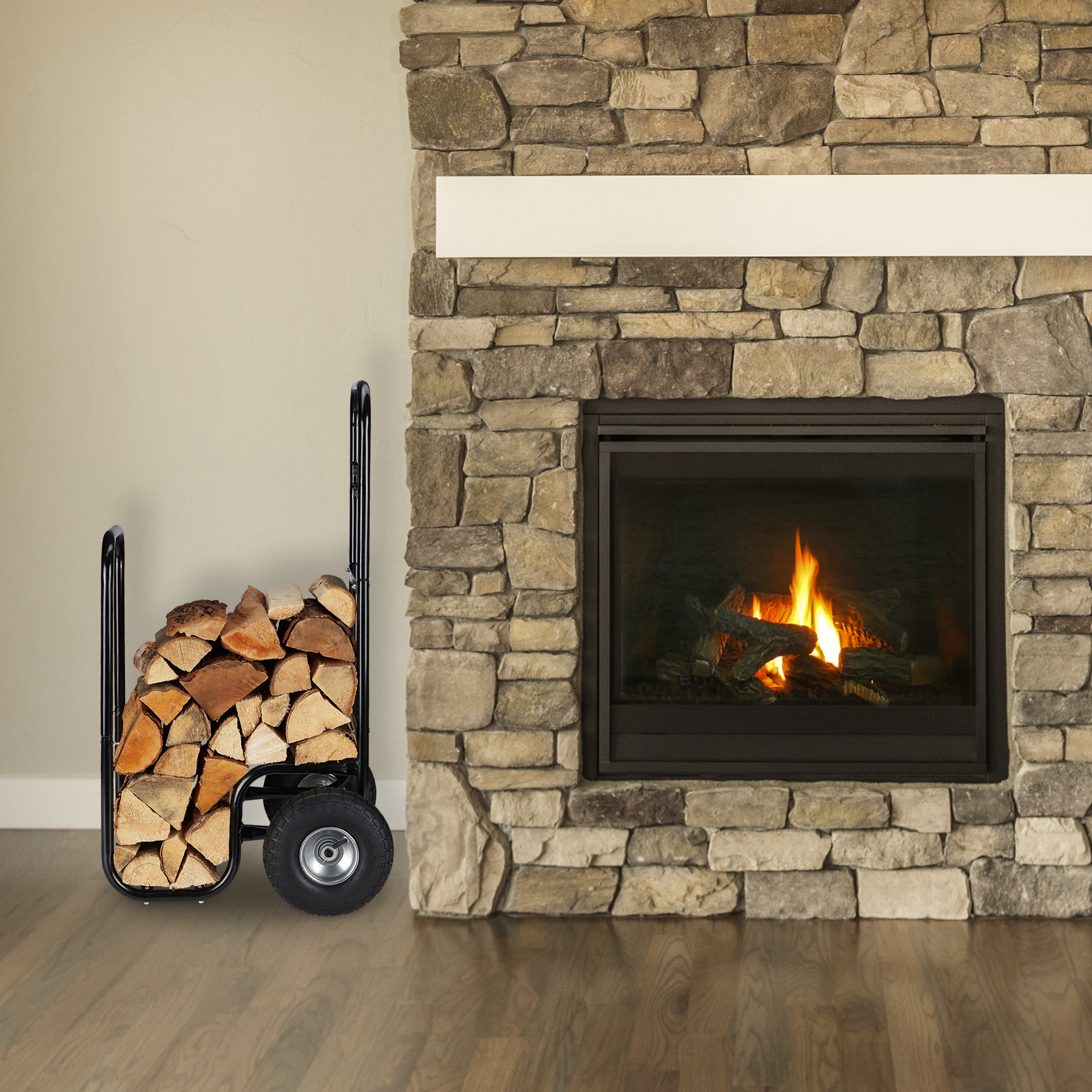 Ein holzgefüllter schwarzer Brennholz-Korb steht vor einem Steinkamin mit brennendem Feuer.