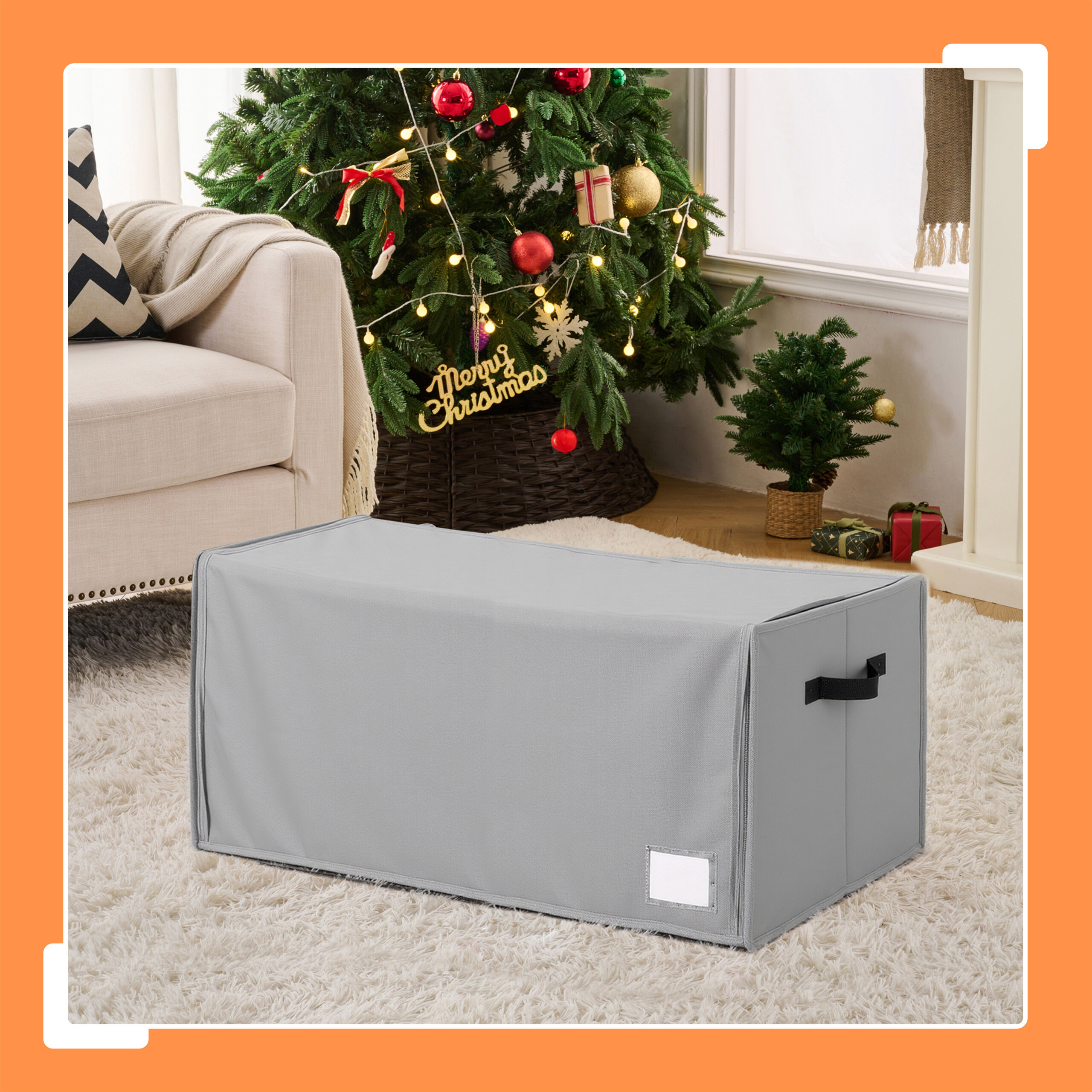 Eine graue Aufbewahrungsbox steht vor einem Weihnachtsbaum in einem Wohnzimmer.