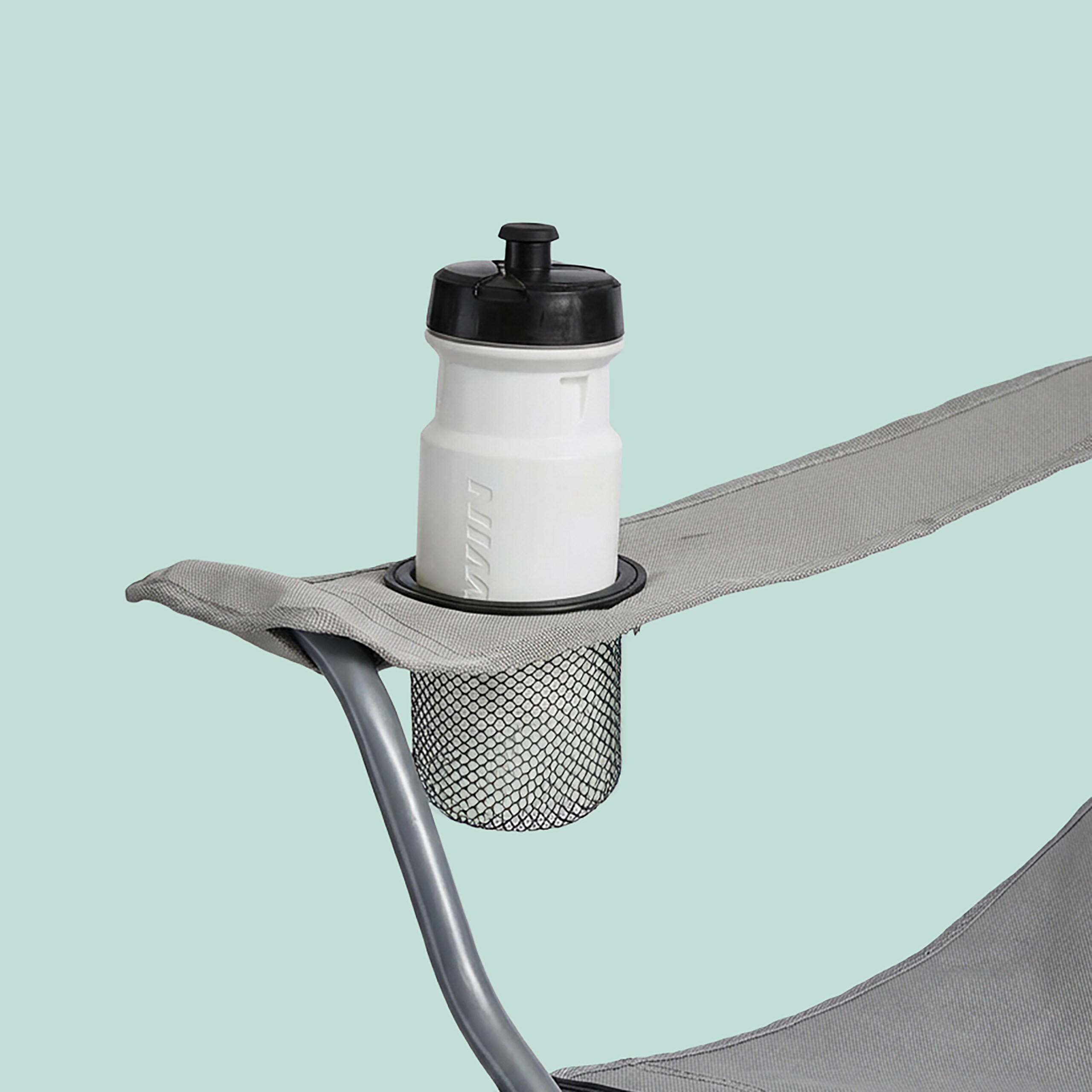 Eine weiße Sportflasche mit schwarzem Deckel steht im Netz-Getränkehalter einer grauen Campingstuhl-Armlehne.