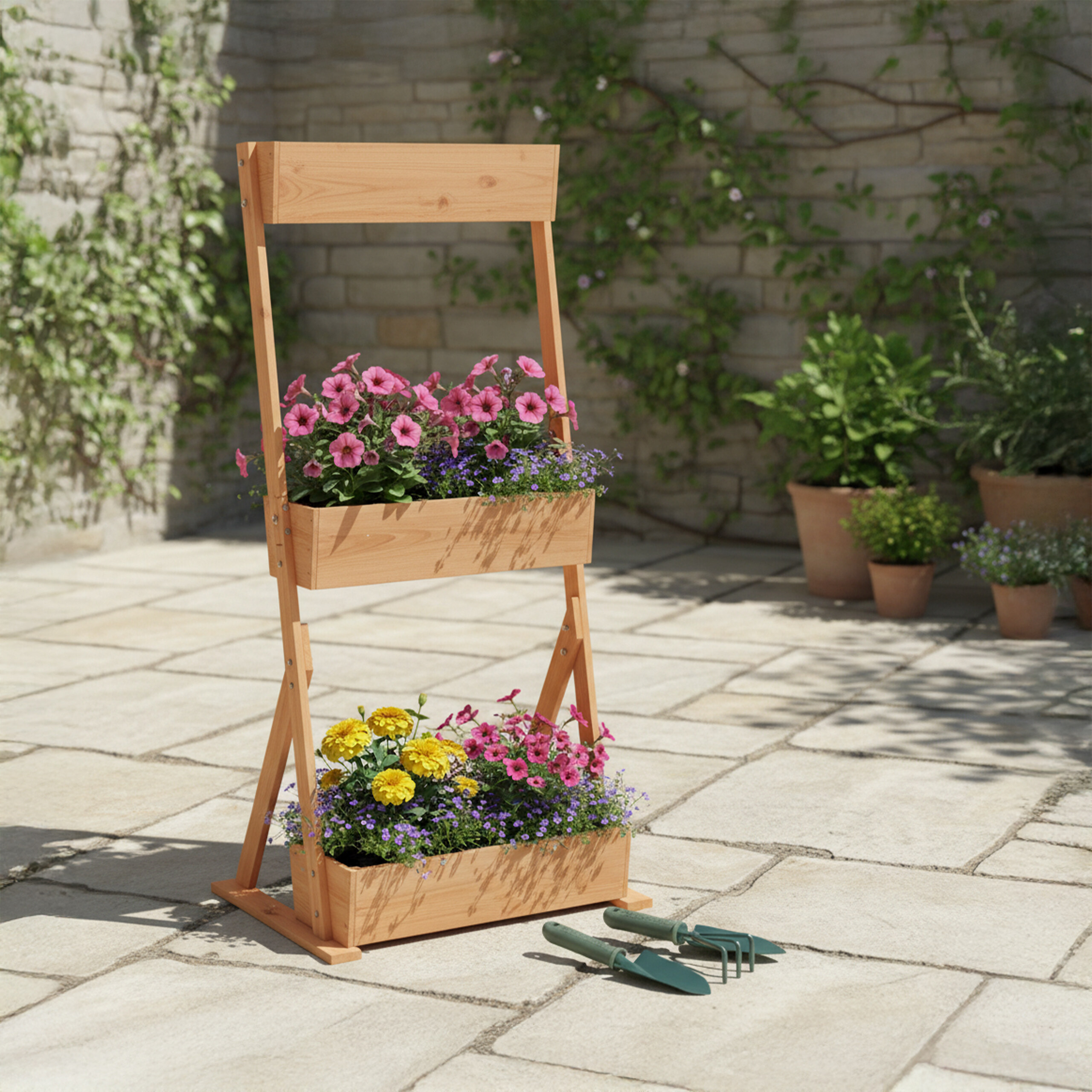 Ein hölzernes Hochbeet mit zwei Etagen bepflanzt mit bunten Blumen, stehend auf einer Terrasse mit Gartengeräten.