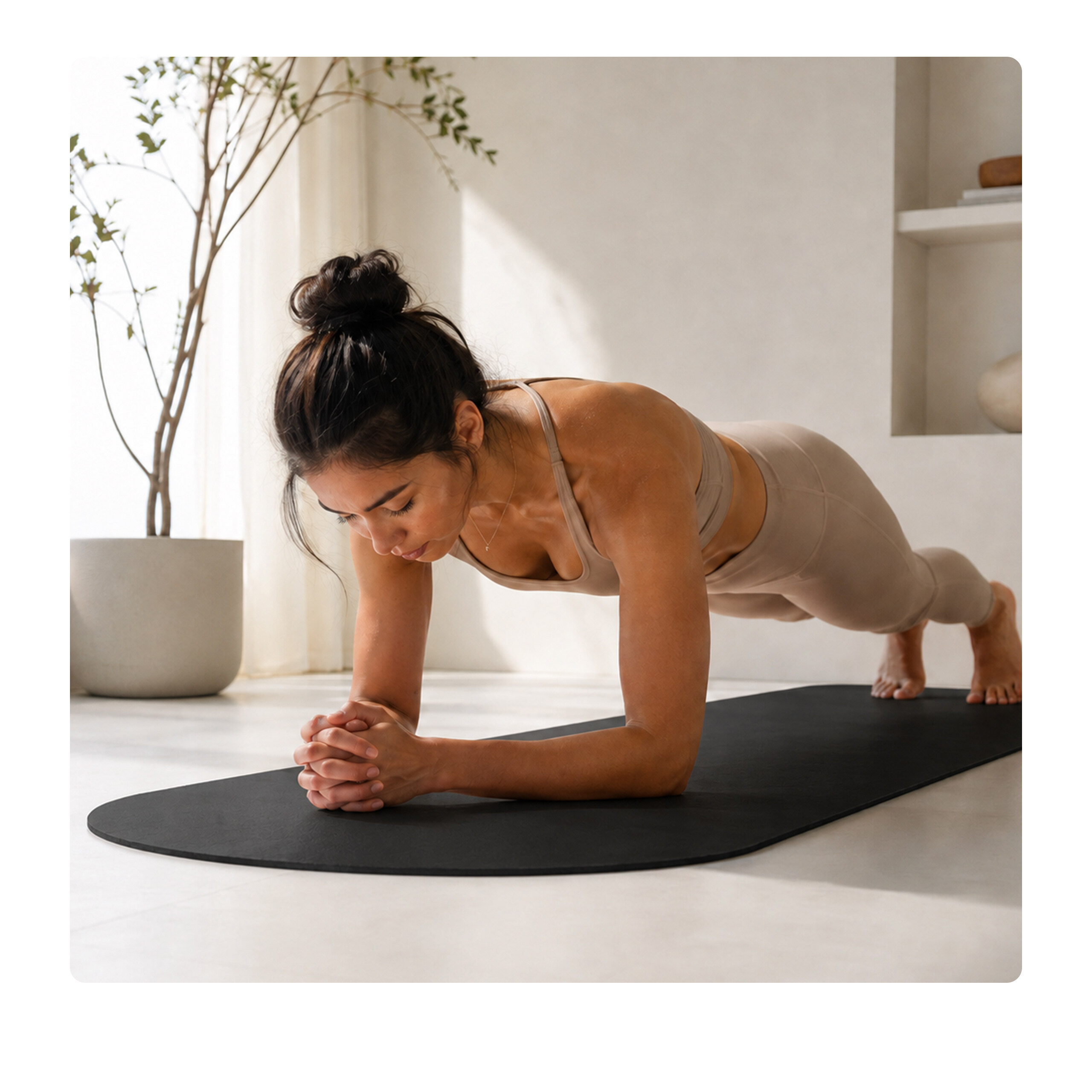 Eine Frau in Sportbekleidung macht eine Plank-Übung auf einer schwarzen Yogamatte in einem hellen Raum.