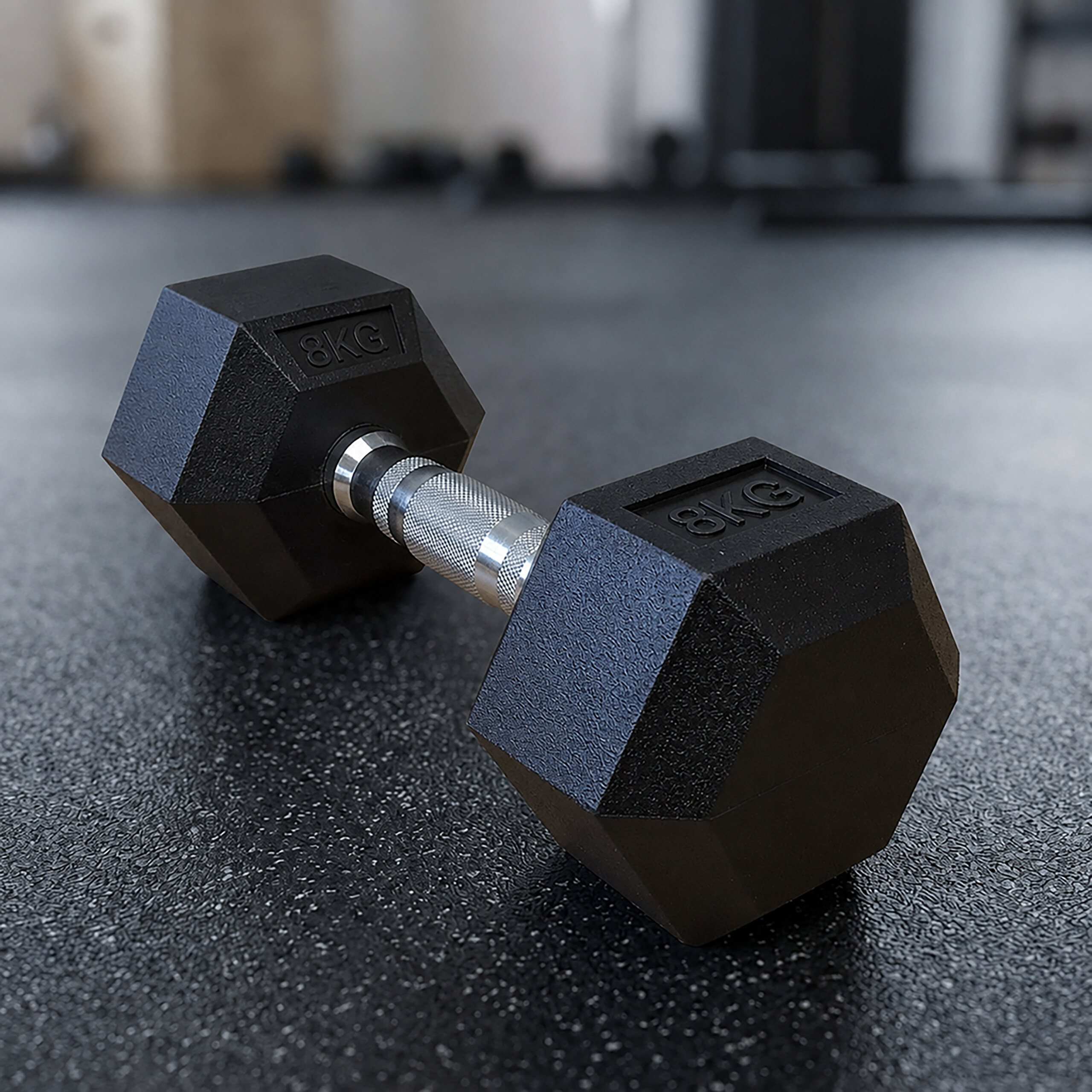 Eine schwarze Achte-Kilo-Hantel liegt auf einem dunklen Gummiboden in einem Fitnessstudio.