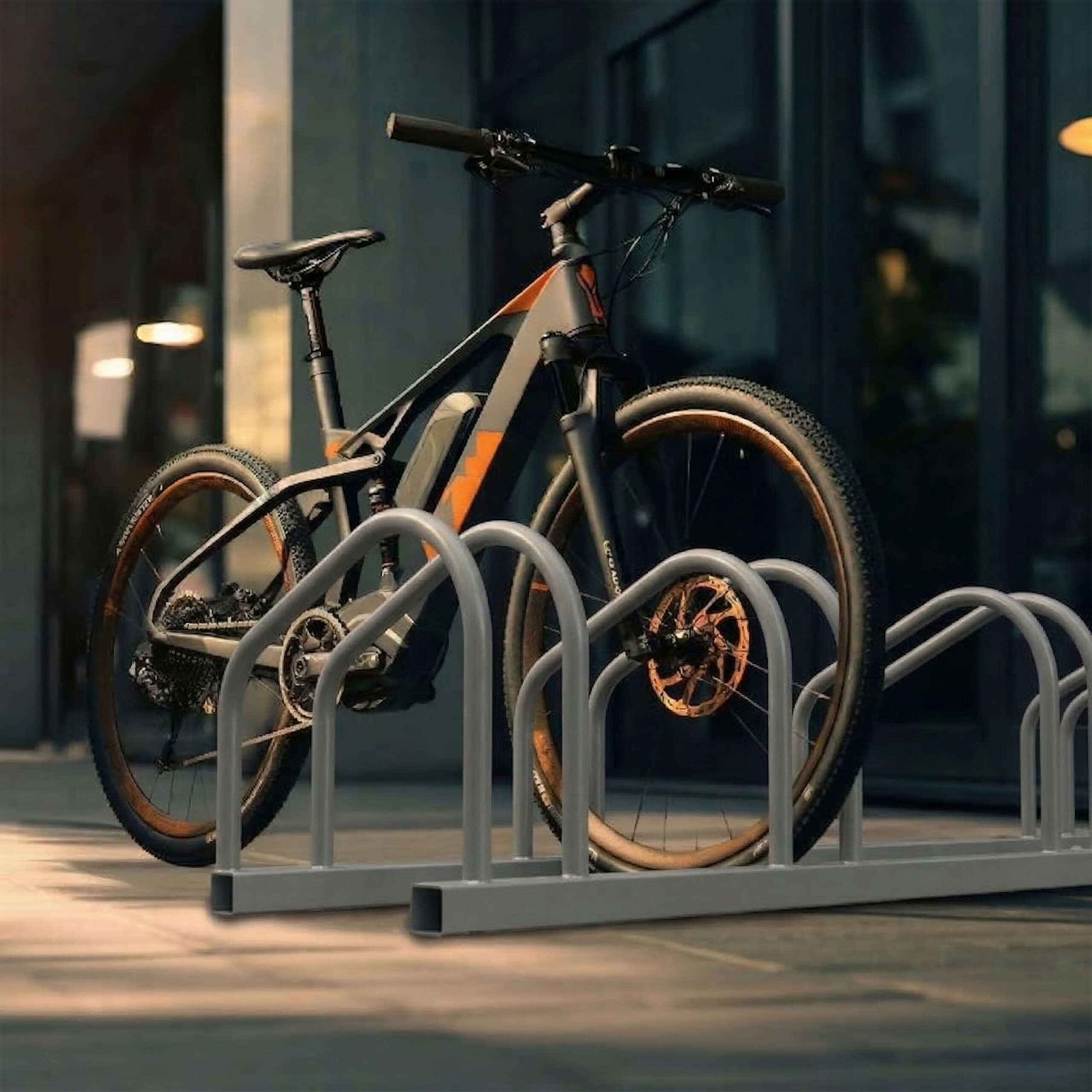 Ein graues und orangefarbenes Elektro-Mountainbike parkt in einem grauen Metall-Fahrradständer.