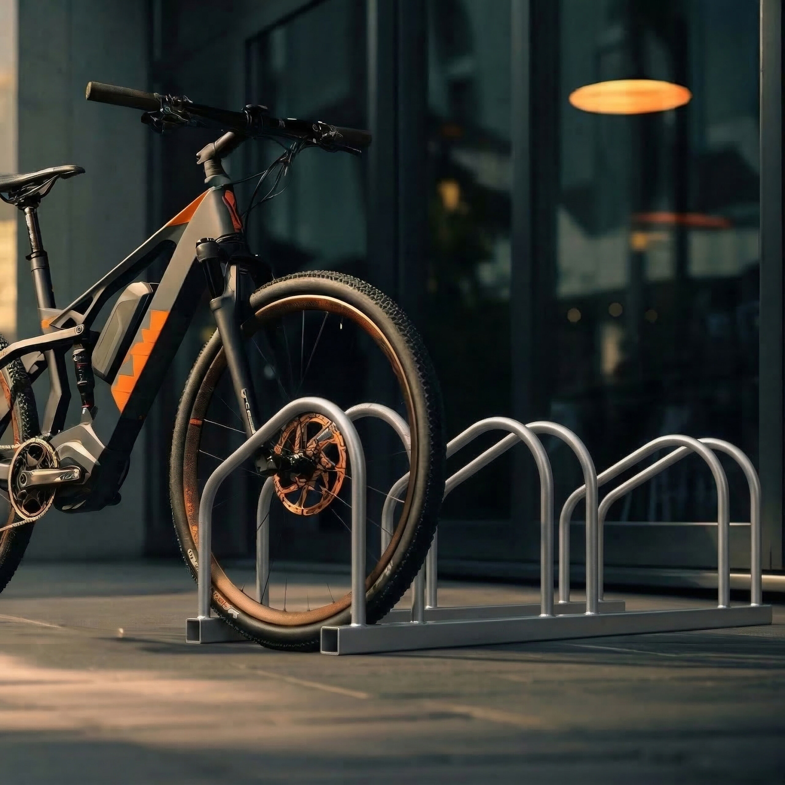 Ein schwarz-oranges Elektrofahrrad steht in einem Metallfahrradständer vor einem modernen Glasgebäude.