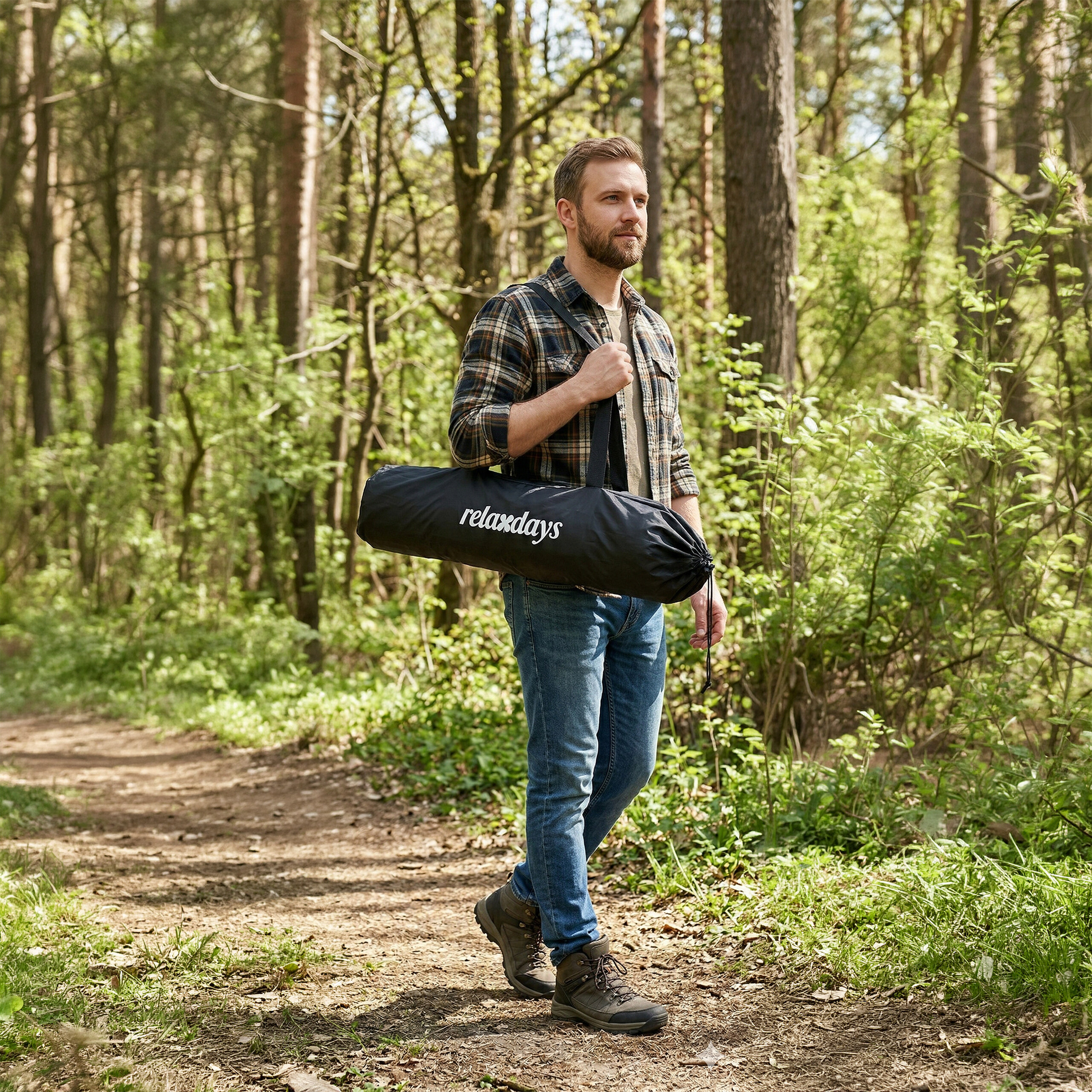 Mann mit kariertem Hemd und Jeans trägt eine schwarze Relaxdays-Tasche auf einem Waldweg.