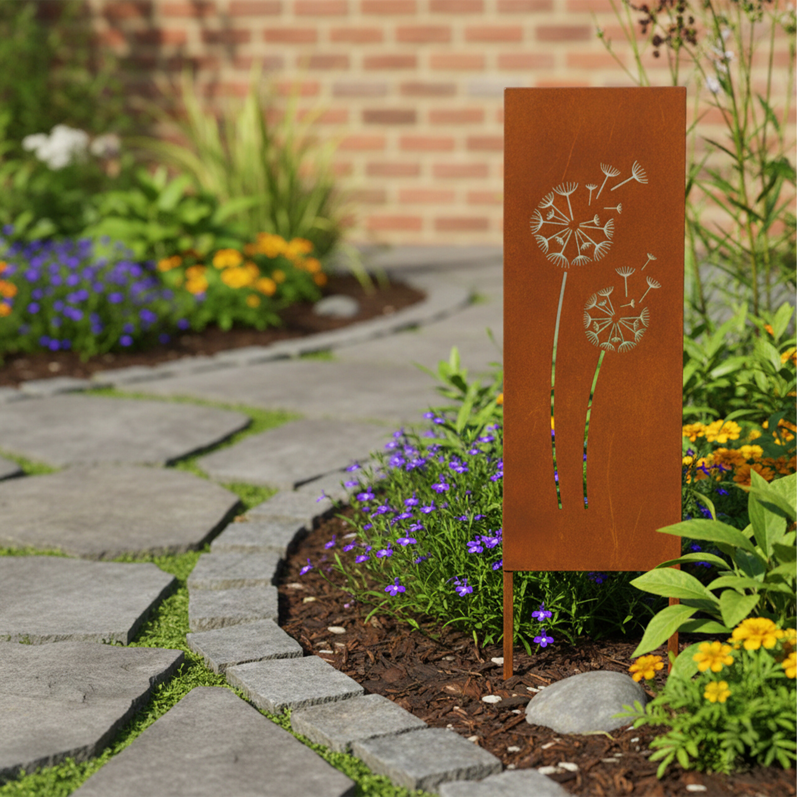 Rostiges Metallschild mit Löwenzahnmotiv in einem Garten mit Steinen und bunten Blumen.