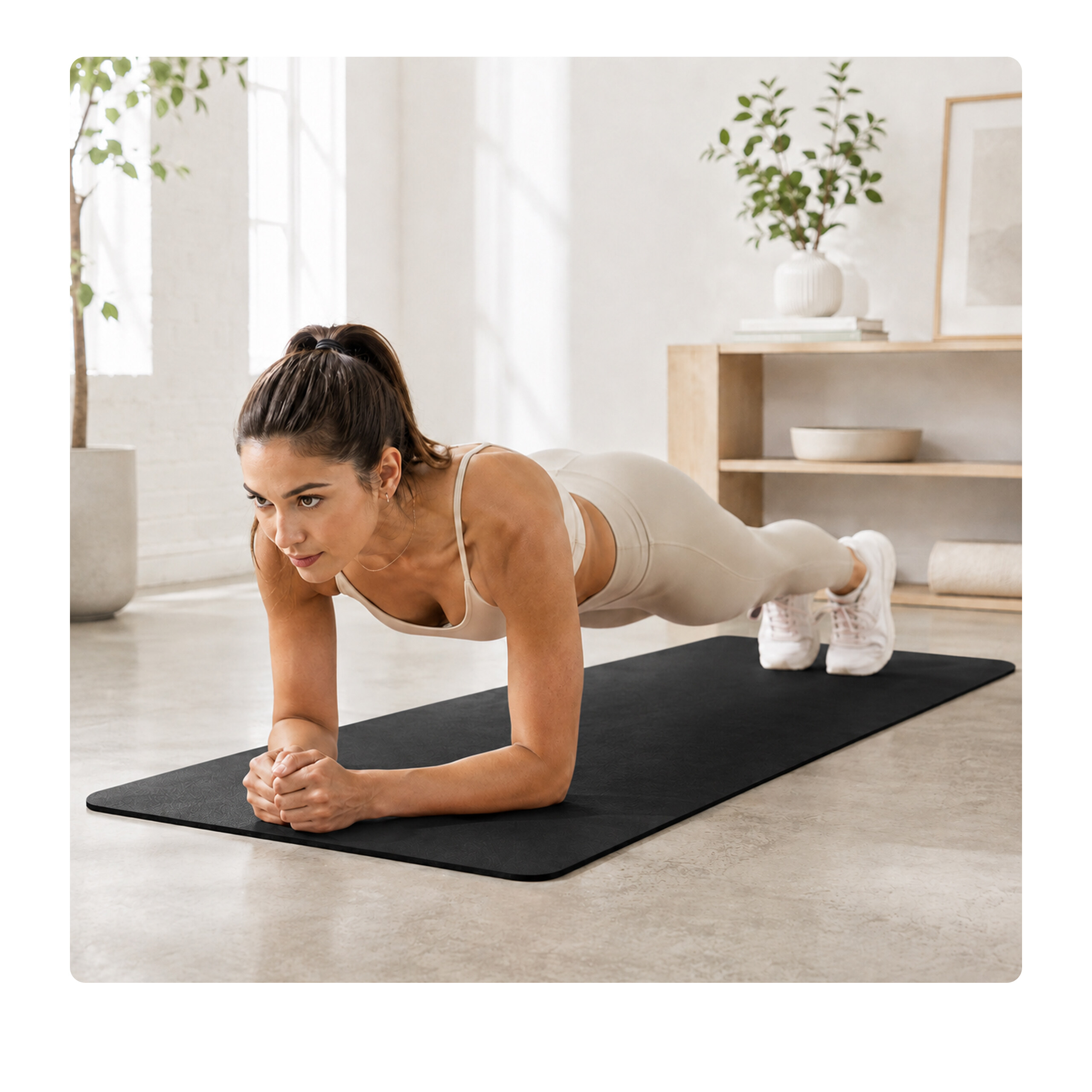 Eine Frau in heller Sportkleidung hält einen Plank auf einer schwarzen Matte in einem hellen Raum.