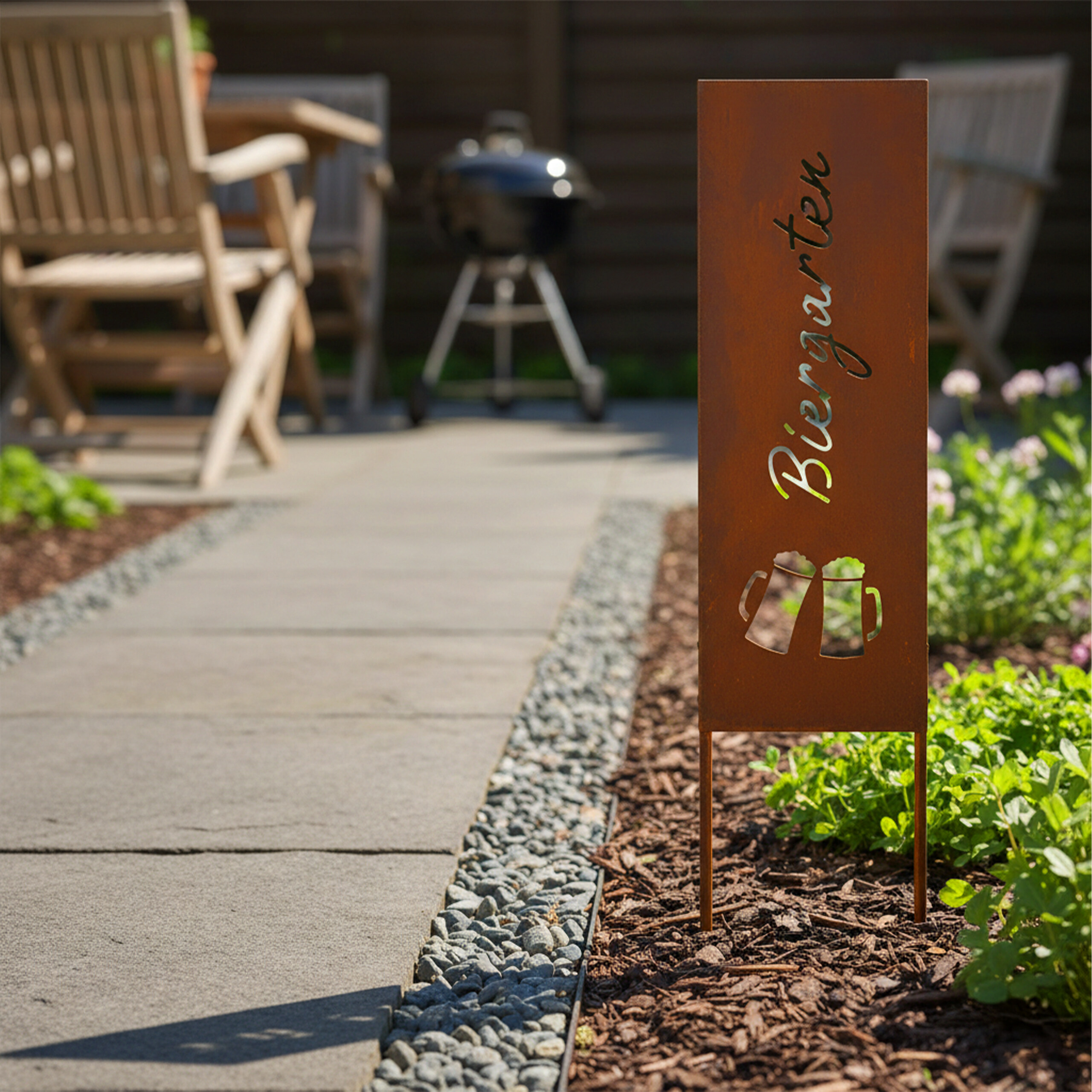 Rostfarbene Metallstele mit der Aufschrift Biergarten und Bierkrug-Motiven in einem Garten.