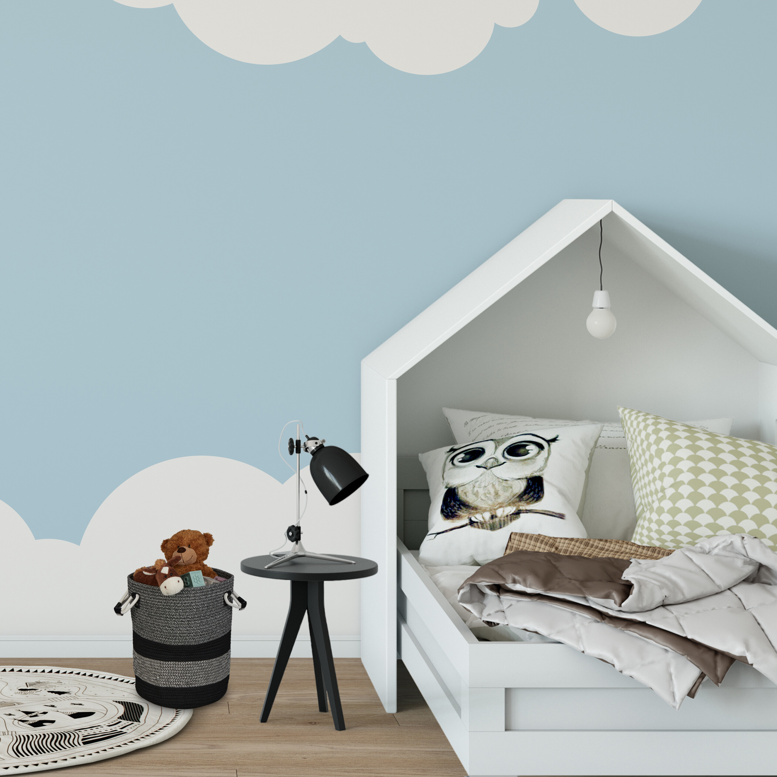 Kindermarkt mit weißem Hausbett, Eulen-Kissen, Nachttisch mit Lampe, Spielzeugkorb vor blau-weißer Wolkenwand.