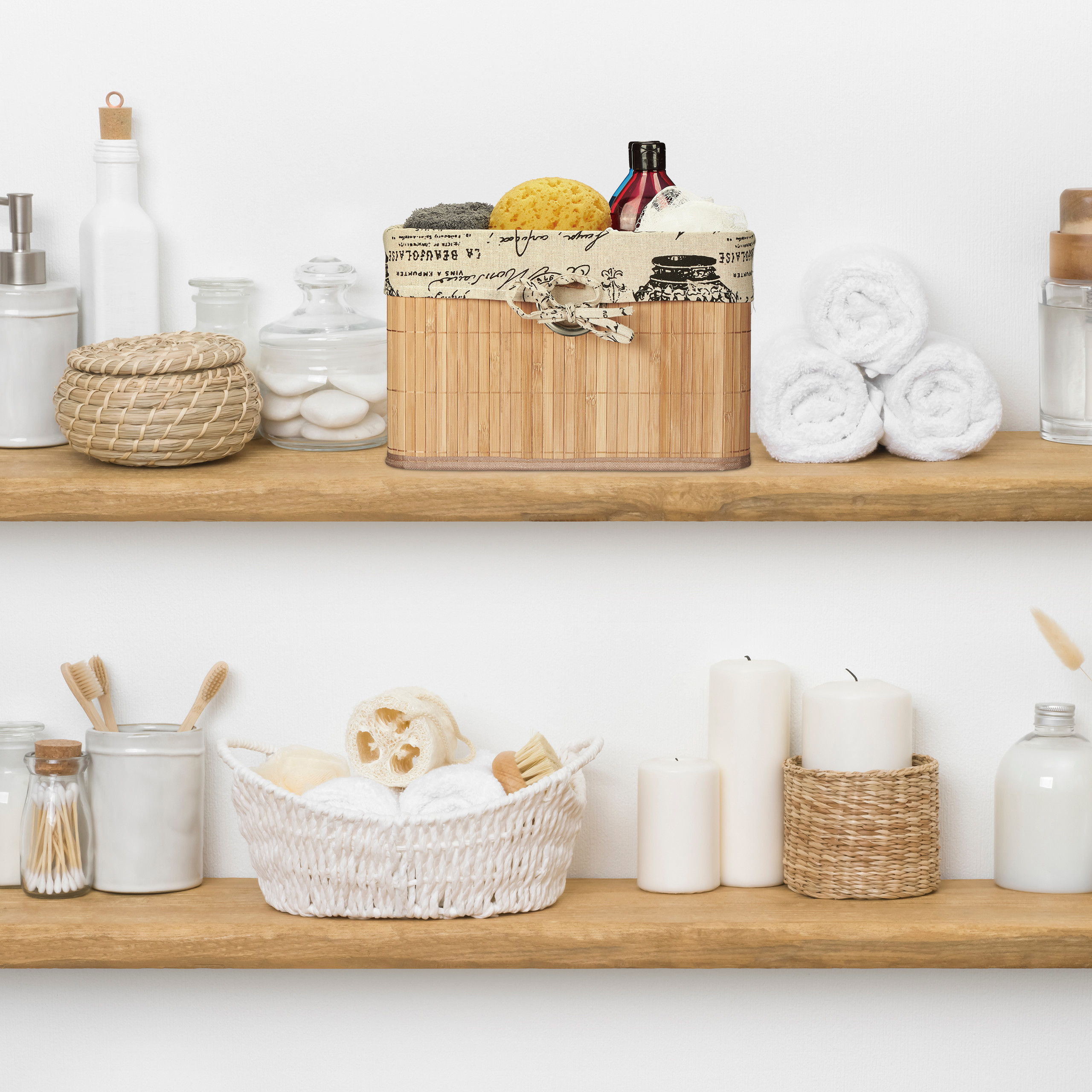 Holzregale an einer weißen Wand mit Badaccessoires, gefalteten Handtüchern, Flaschen, Kerzen und geflochtenen Körben.