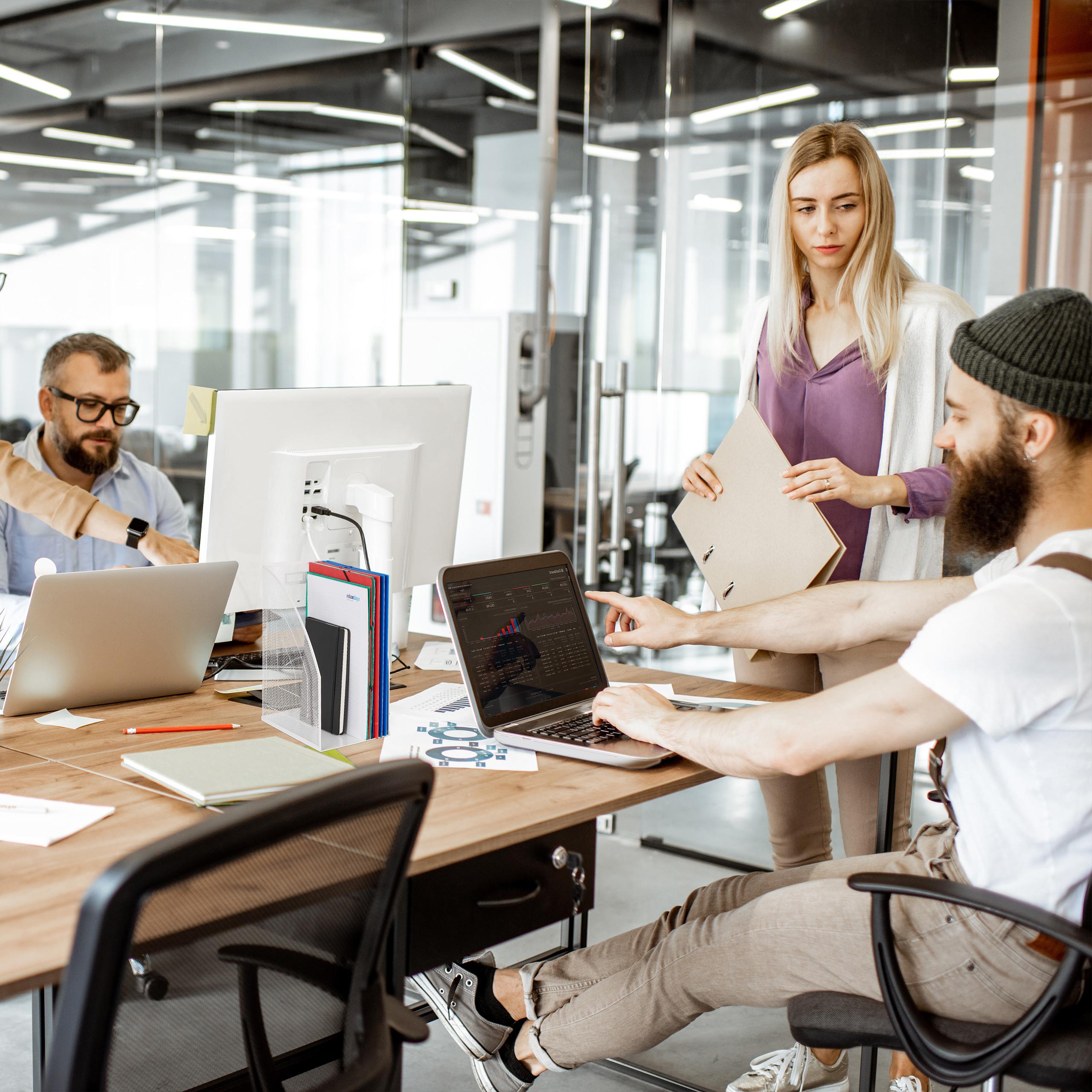Kollegen arbeiten in einem modernen Büro zusammen, nutzen Laptops und besprechen Daten.