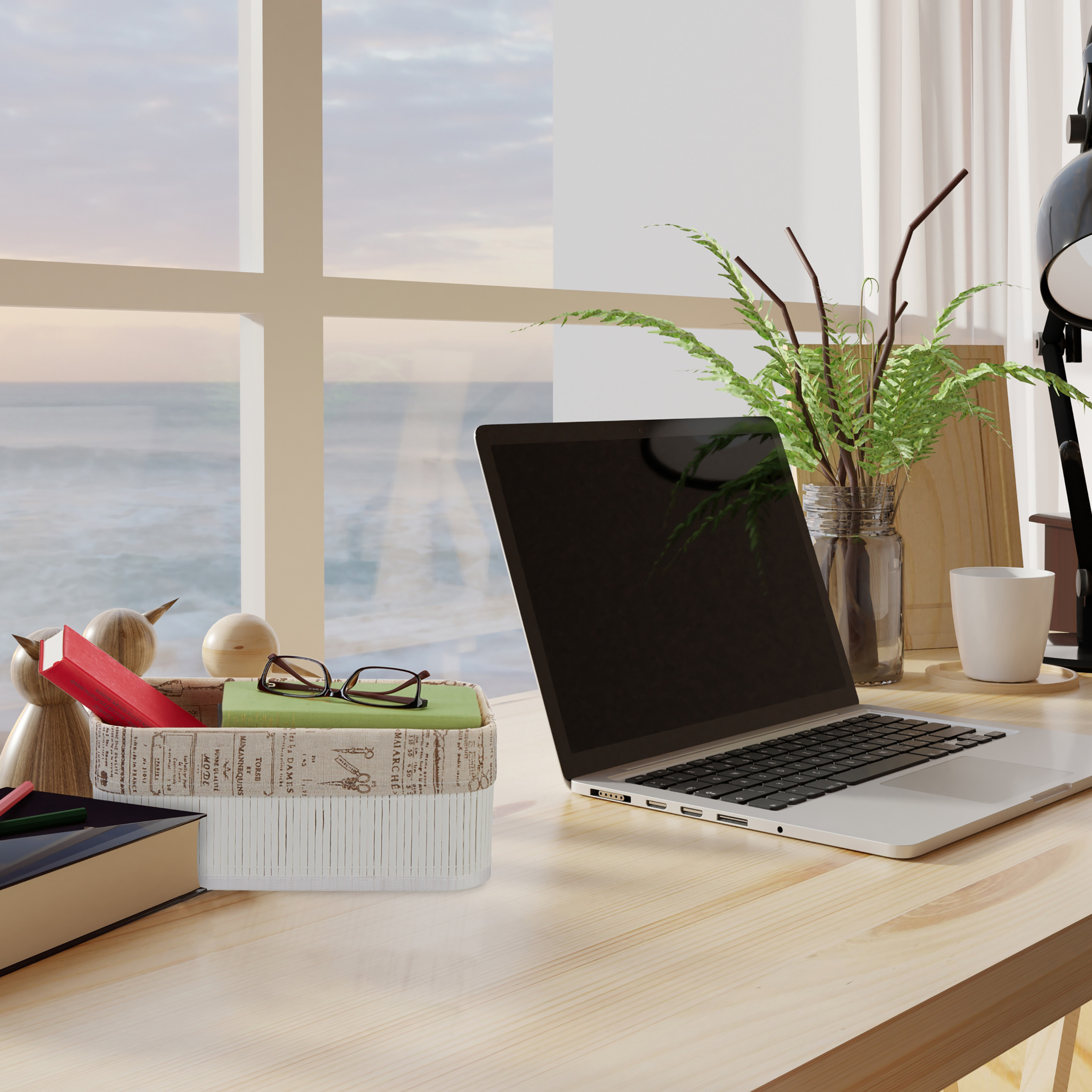 Schreibtisch am Meer mit Laptop, Pflanzen in Vase und Büchern.