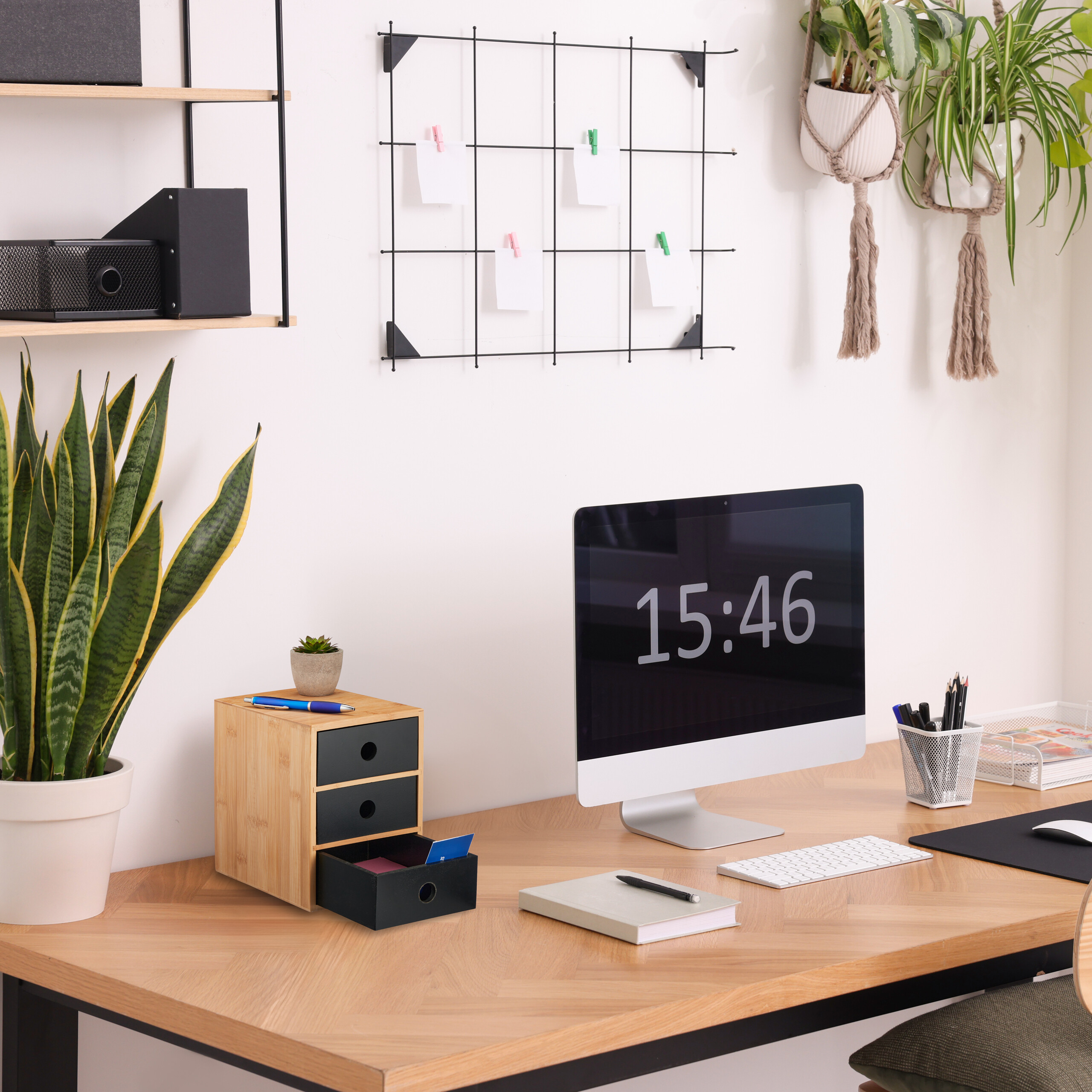 Moderner Schreibtisch mit Computer, Organizer, Pflanzen und Notizgitter an der Wand.