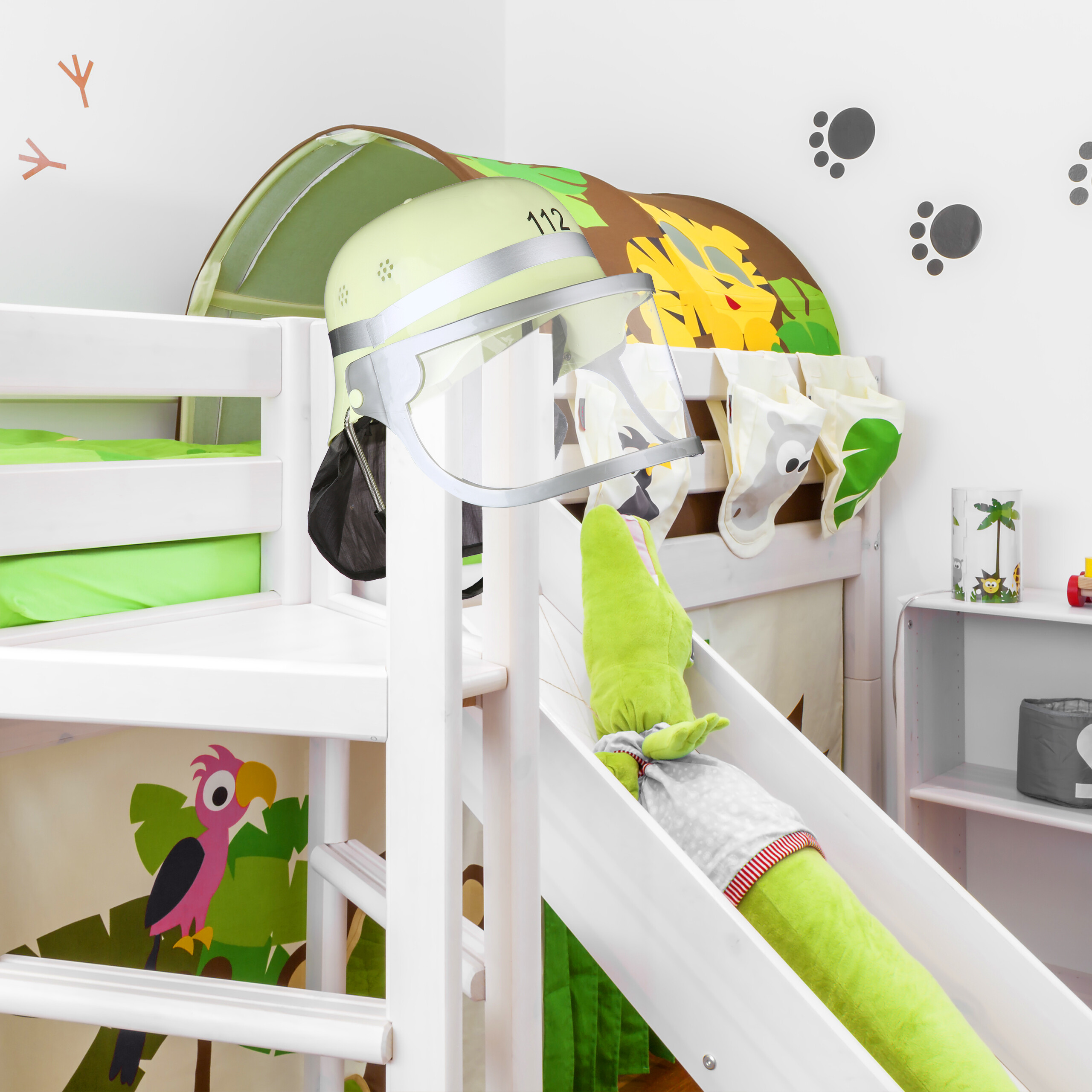 Ein Feuerwehrhelm hängt am Kinderbett mit Rutsche, auf der ein Plüschkrokodil sitzt.