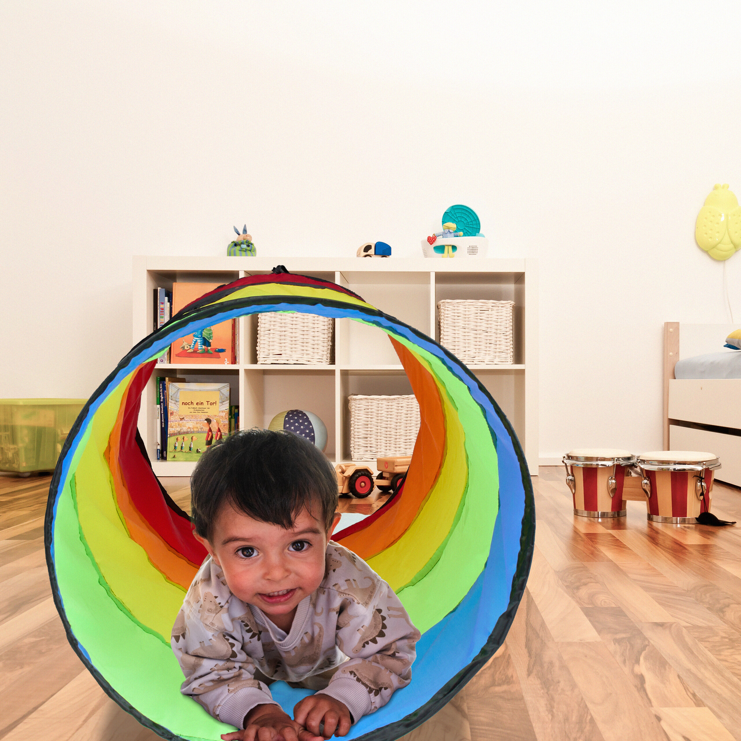 Kleinkind krabbelt durch einen bunten Spieltunnel in einem kinderzimmer.