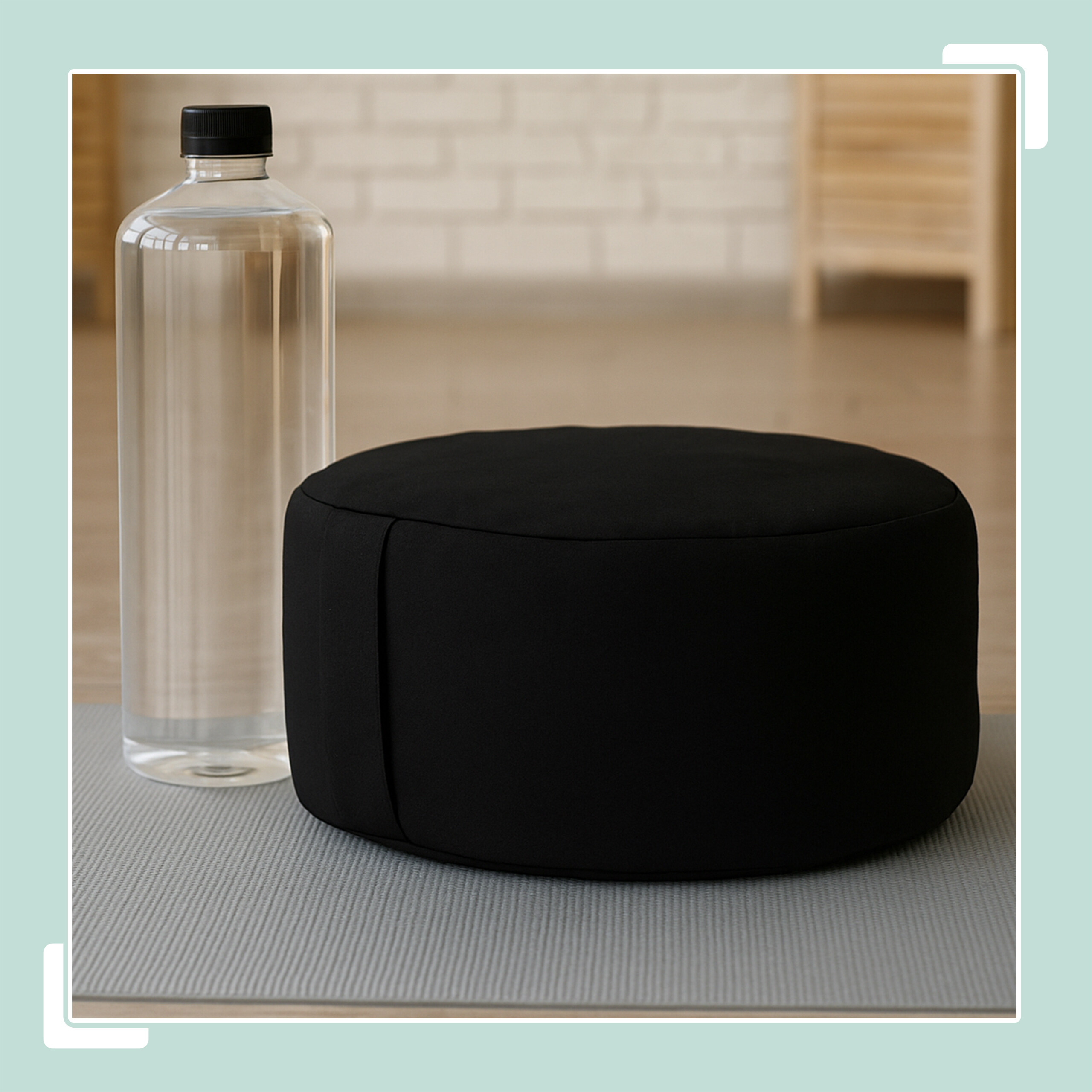 Ein schwarzes Meditationskissen und eine Wasserflasche auf einer grauen Matte in einem Raum.