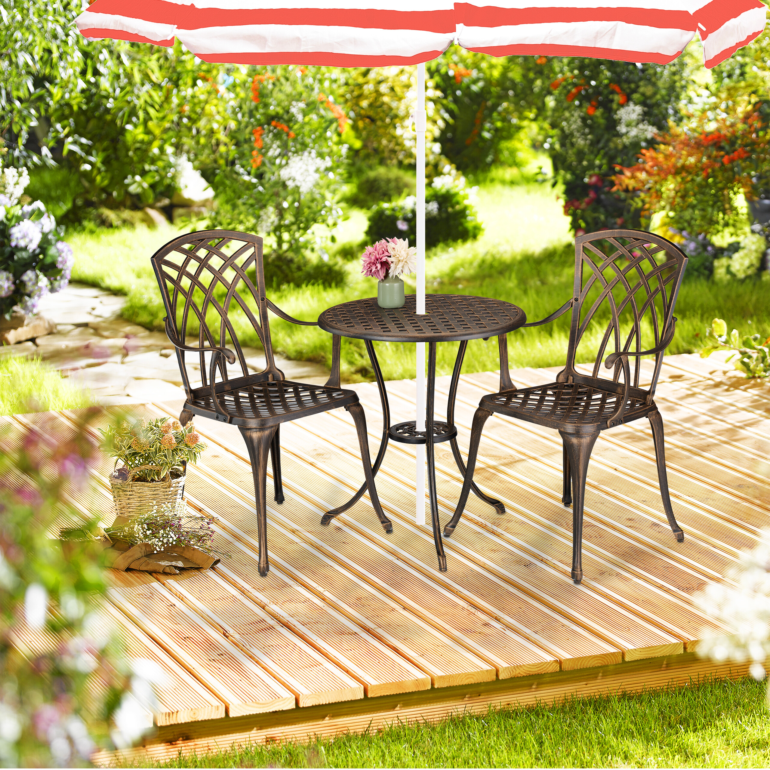 Ein Bistroset mit Tisch und zwei Stühlen unter einem rot-weißen Sonnenschirm auf einer Holzterrasse im Garten.