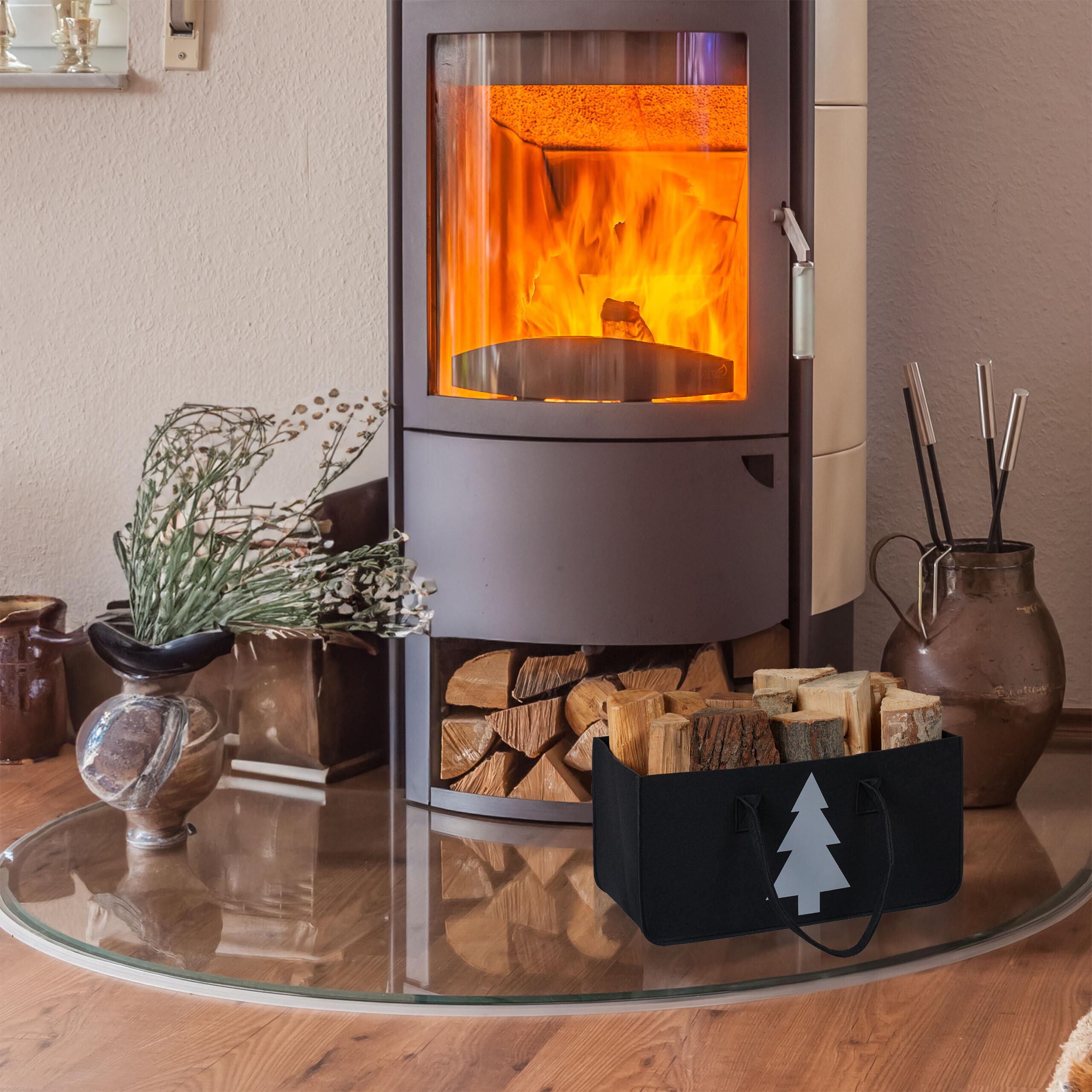 Ein Kaminofen mit brennendem Feuer, Holzscheite im Fach darunter und eine Holztasche mit Tannenmotiv davor.