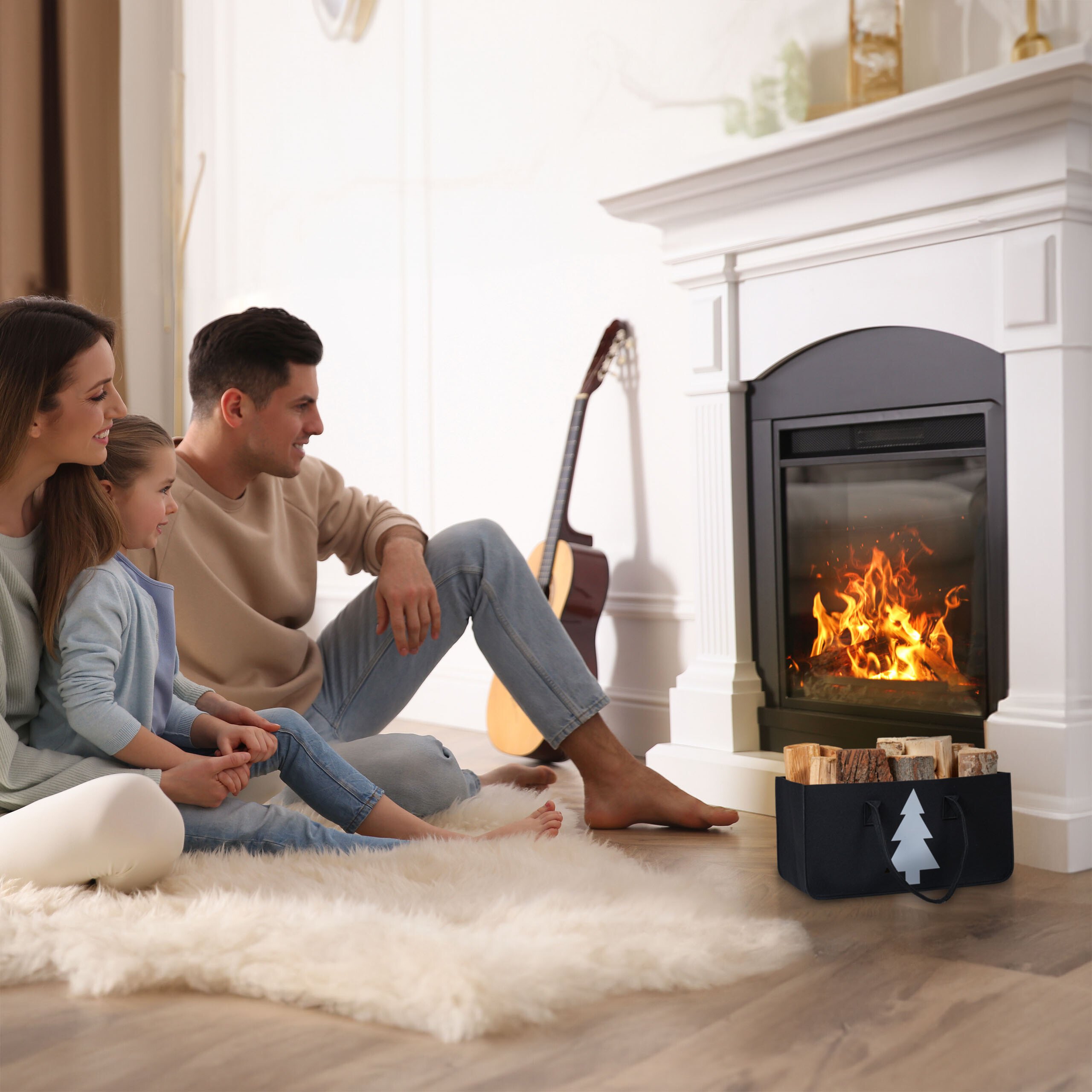 Eine Familie sitzt auf einem Fell vor einem gemütlichen Kamin mit Holz.