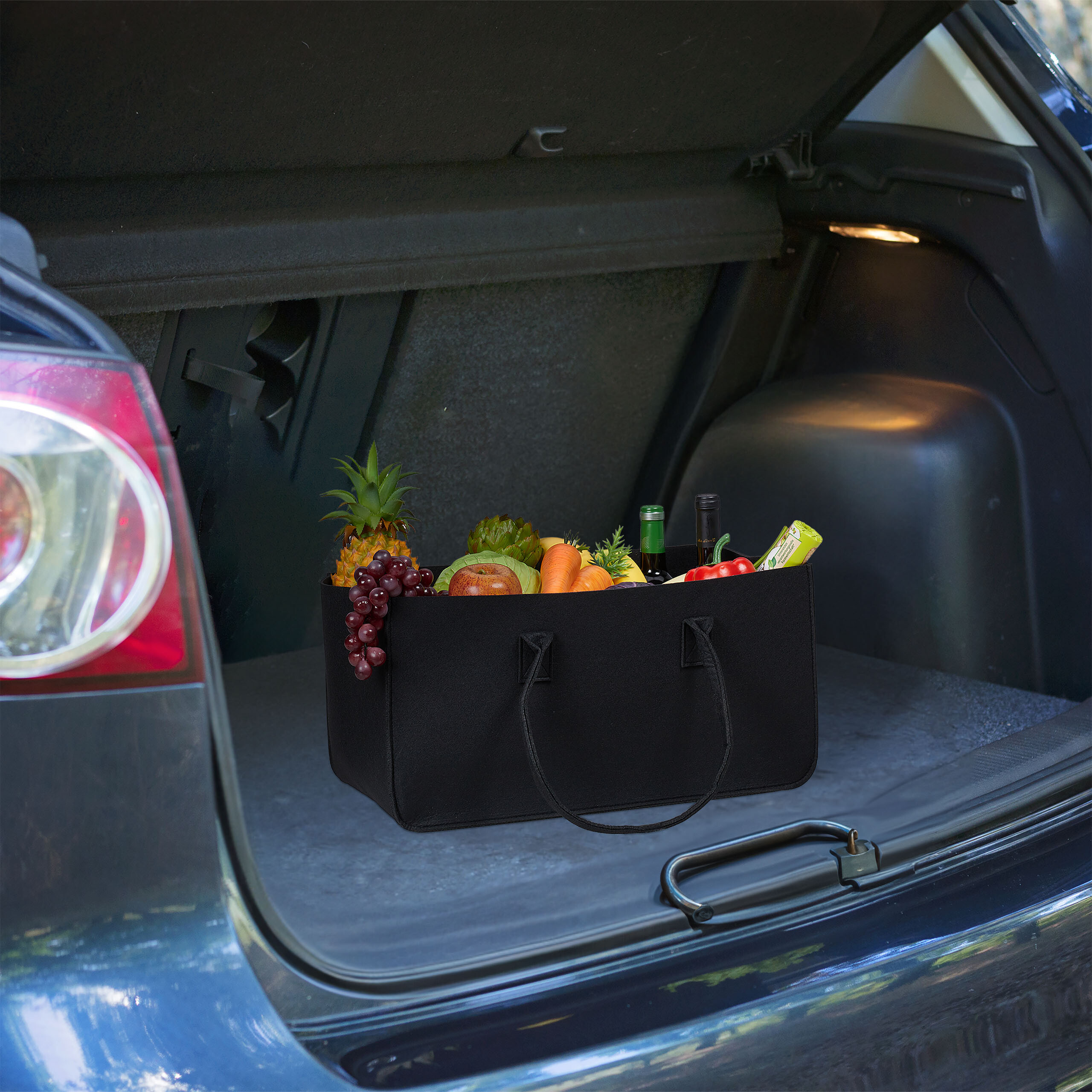 Eine schwarze Tasche voller frischer Früchte und Gemüse steht im Kofferraum eines Autos.