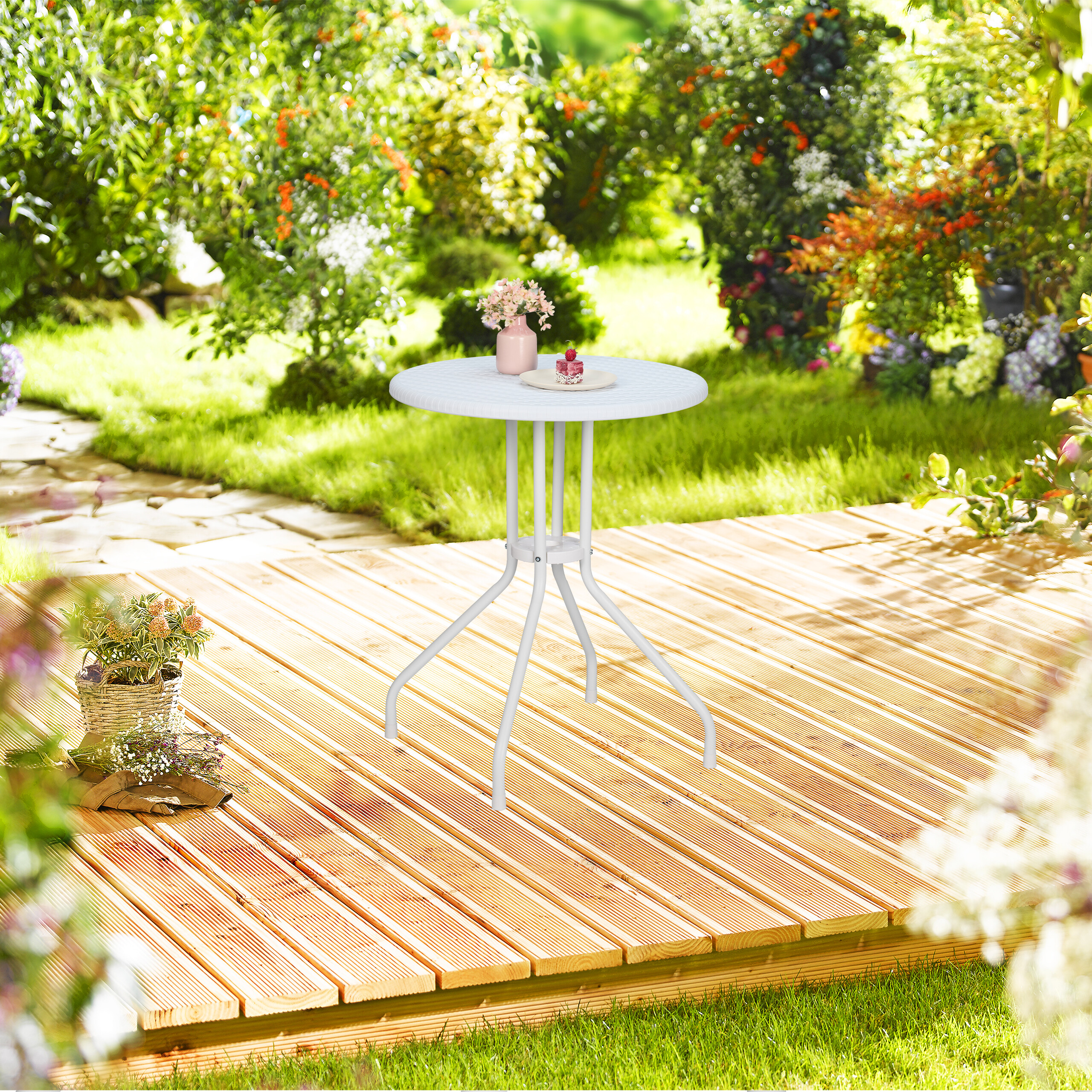 Ein weißer Tisch auf einer Holzterrasse in einem sonnigen Garten.