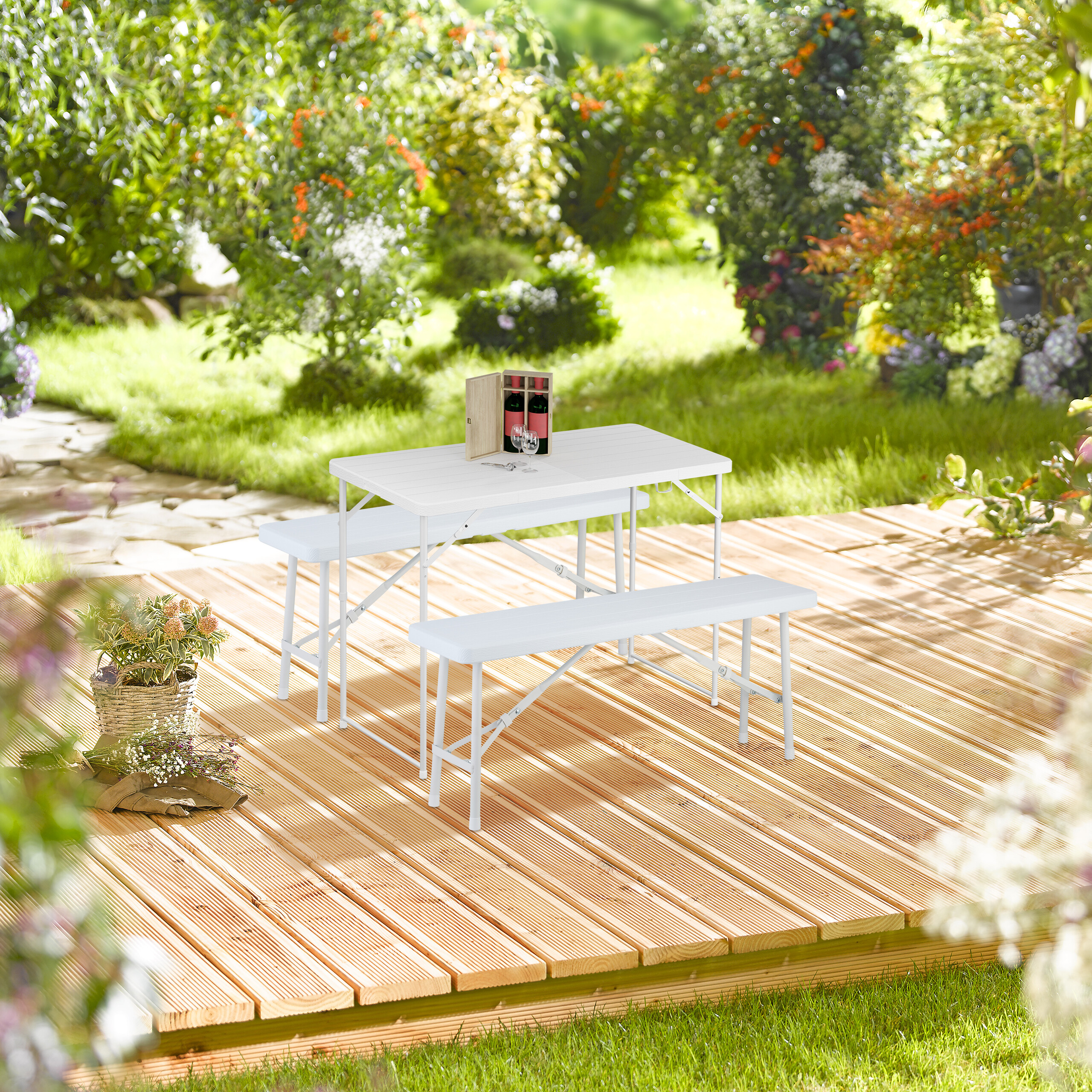 Eine weiße Klapp-Sitzgruppe auf Holzterrasse im Garten.