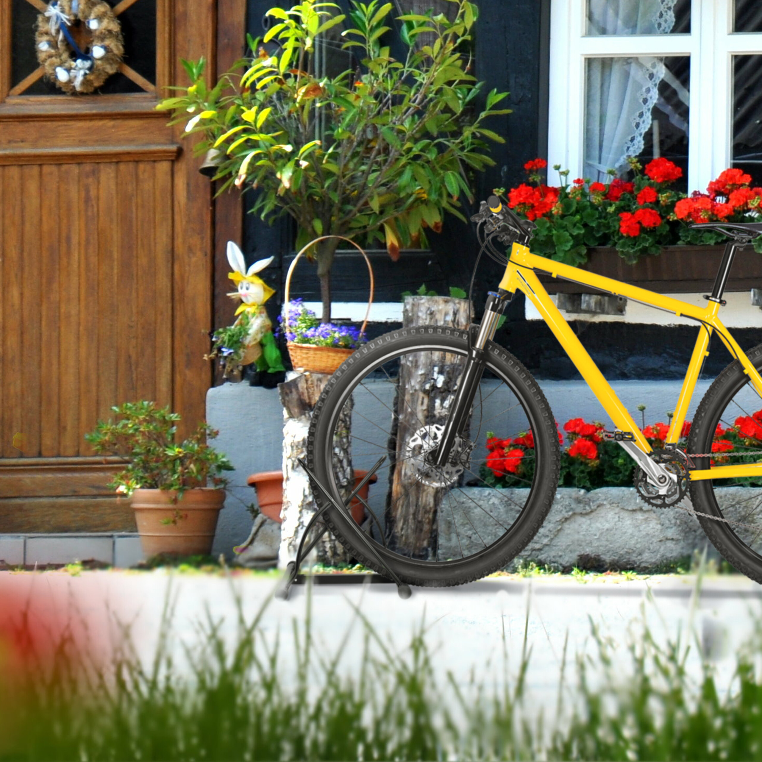 Ein hellgelbes Fahrrad steht vor einem rustikalen Holzhaus mit roten Blumen.